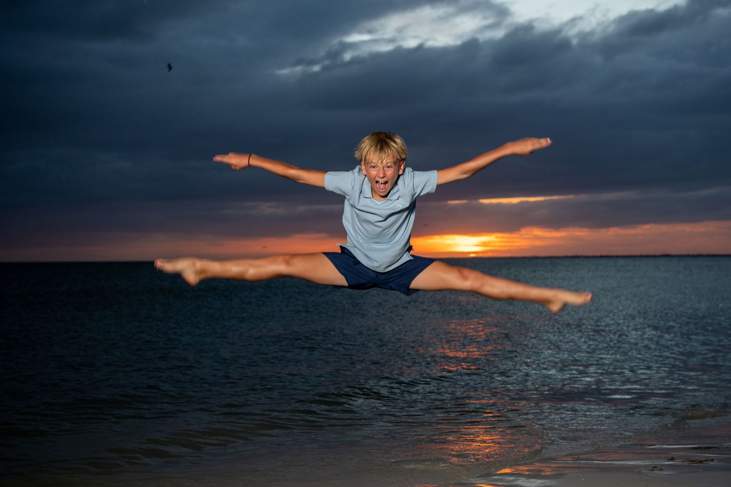 People posing with outstretched arms against dramatic sunset sky over ocean. Beach photoshoot. Family photoshoot,