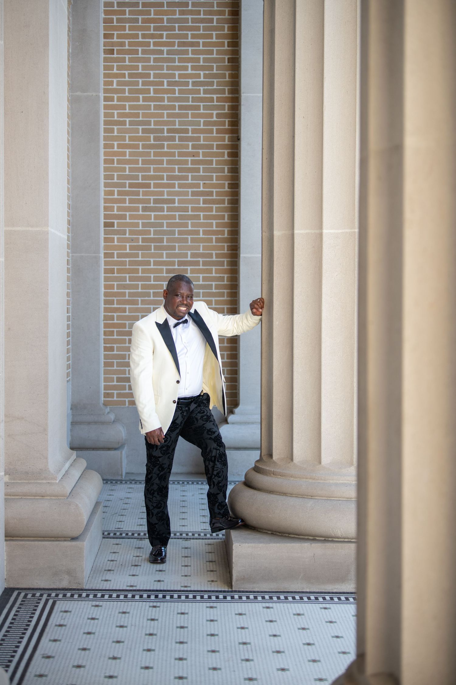 Artistic portrait between classical columns with dramatic lighting and architecture.