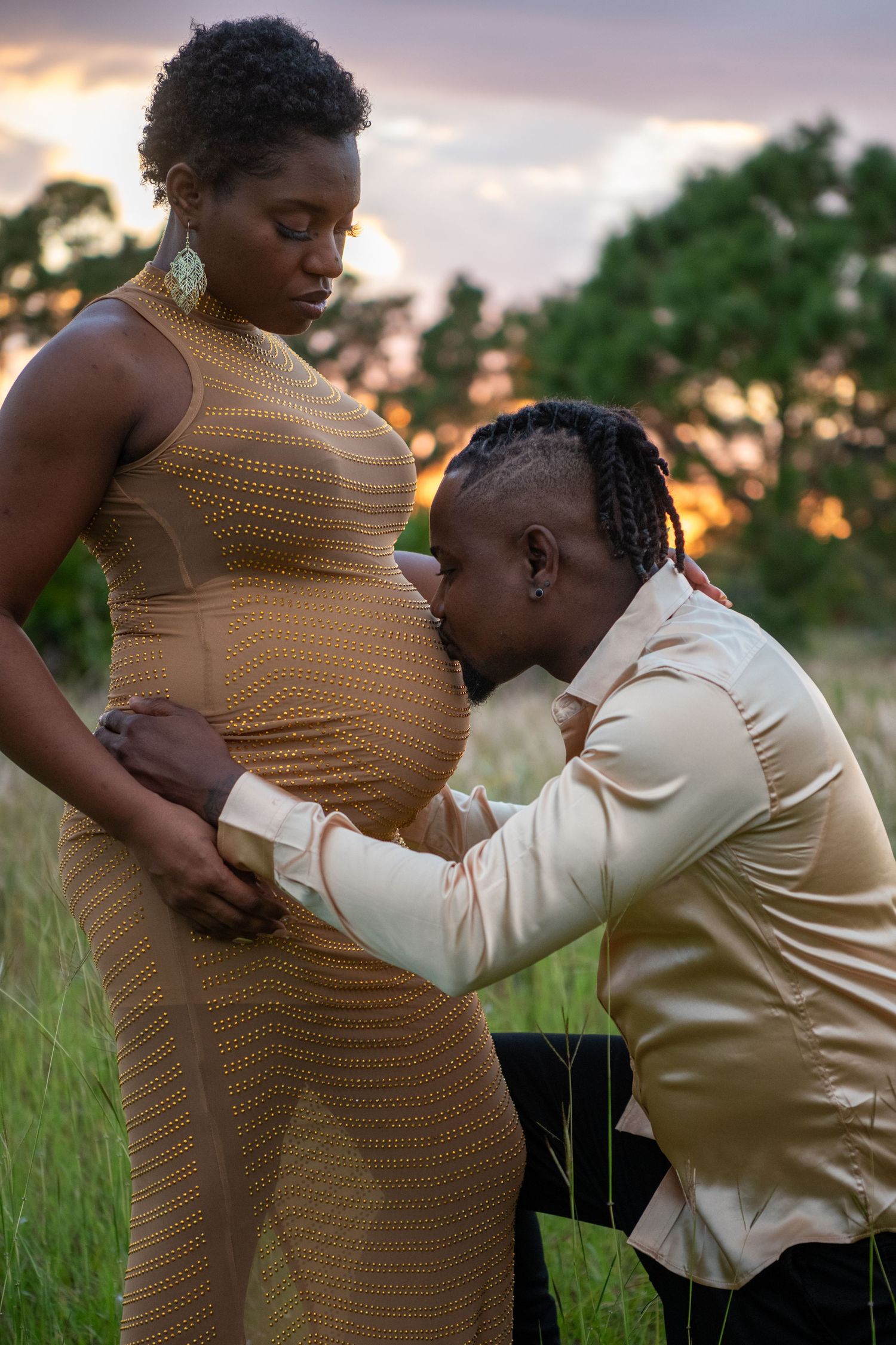 Intimate maternity moment captured in field during golden hour. Maternity photoshoot.