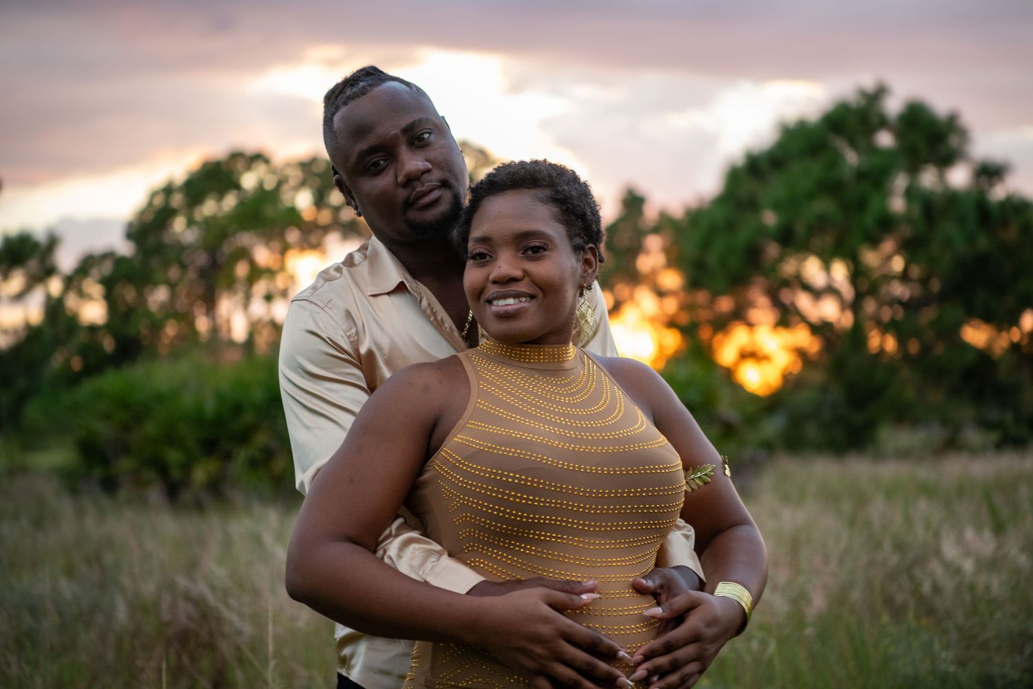 Joyful couple sharing loving moment during outdoor maternity session at sunset. Maternity photoshoot.