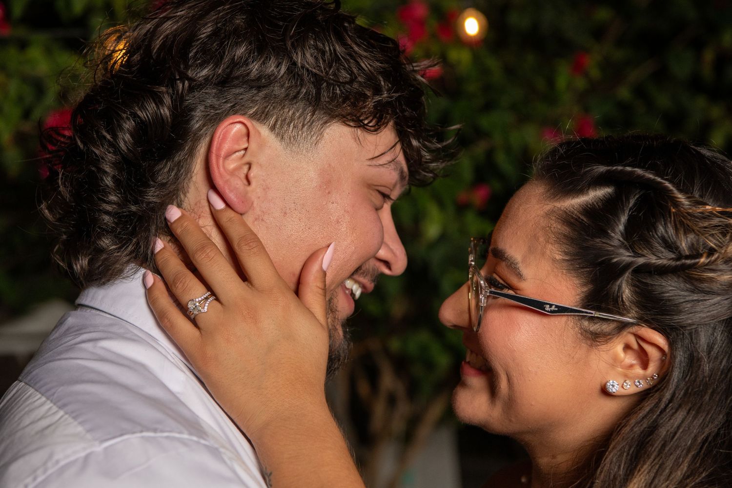 An intimate close-up of a couple sharing a joyful moment against a background of red flowers. Wedding photography.