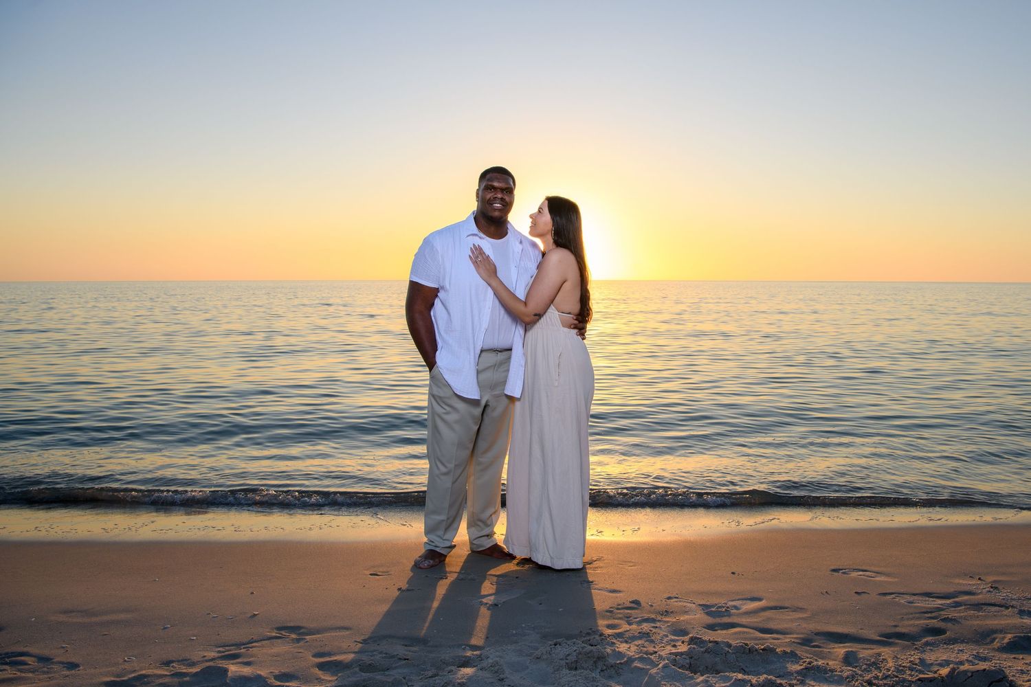 Romantic beach photoshoot with couple embracing at sunset. Engagement photoshoot. Couples photos.