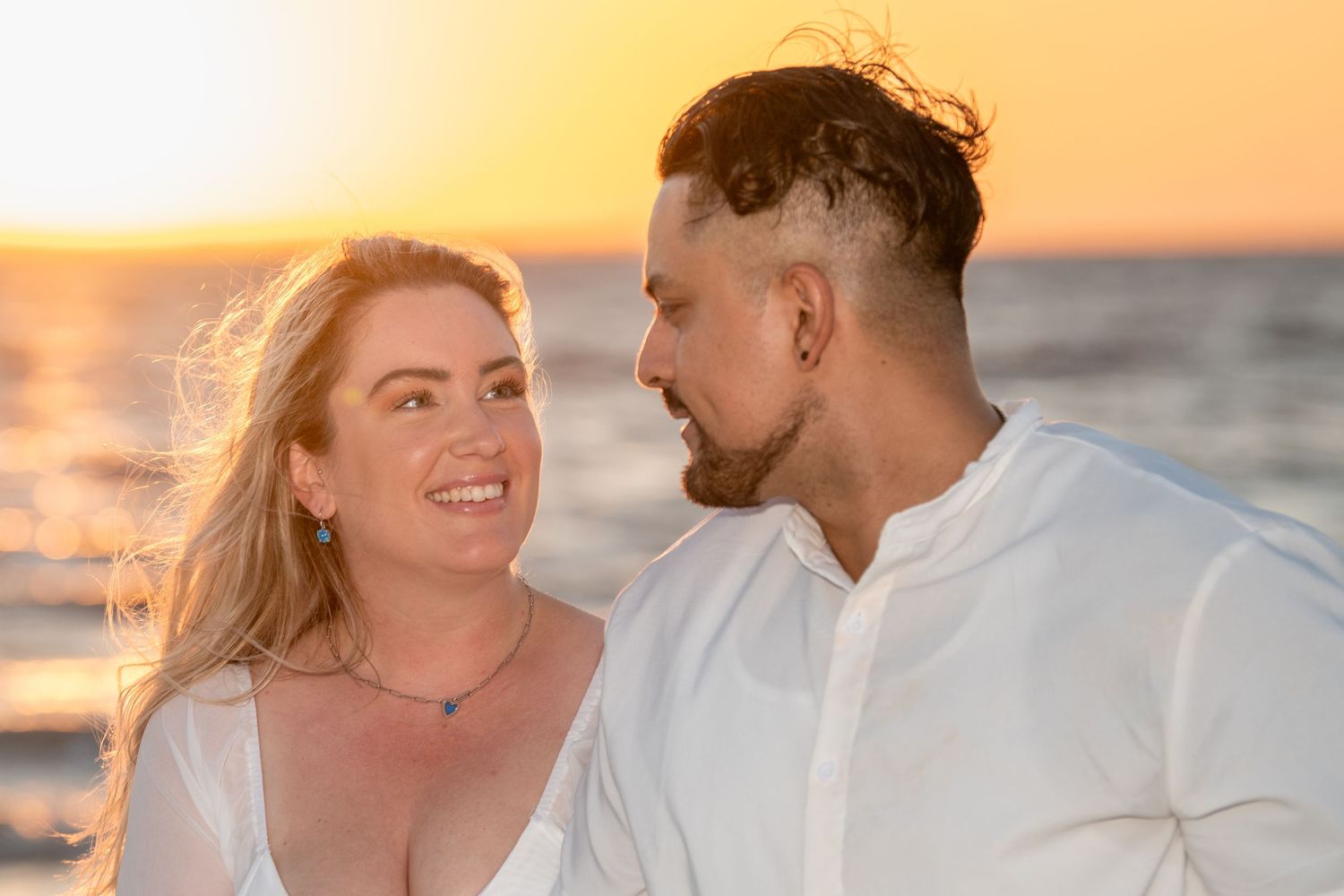 Candid beach photography session with couple during magical golden hour lighting.