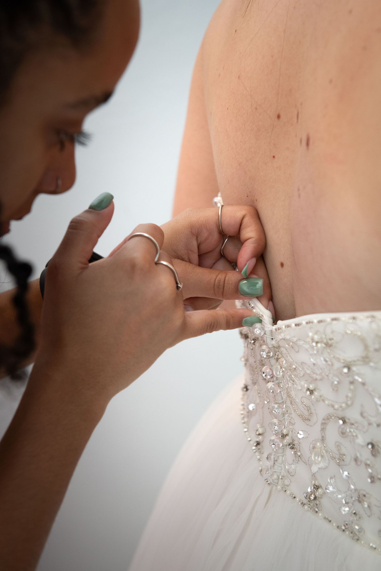 Detail shots of wedding dress beading and embellishments being adjusted.