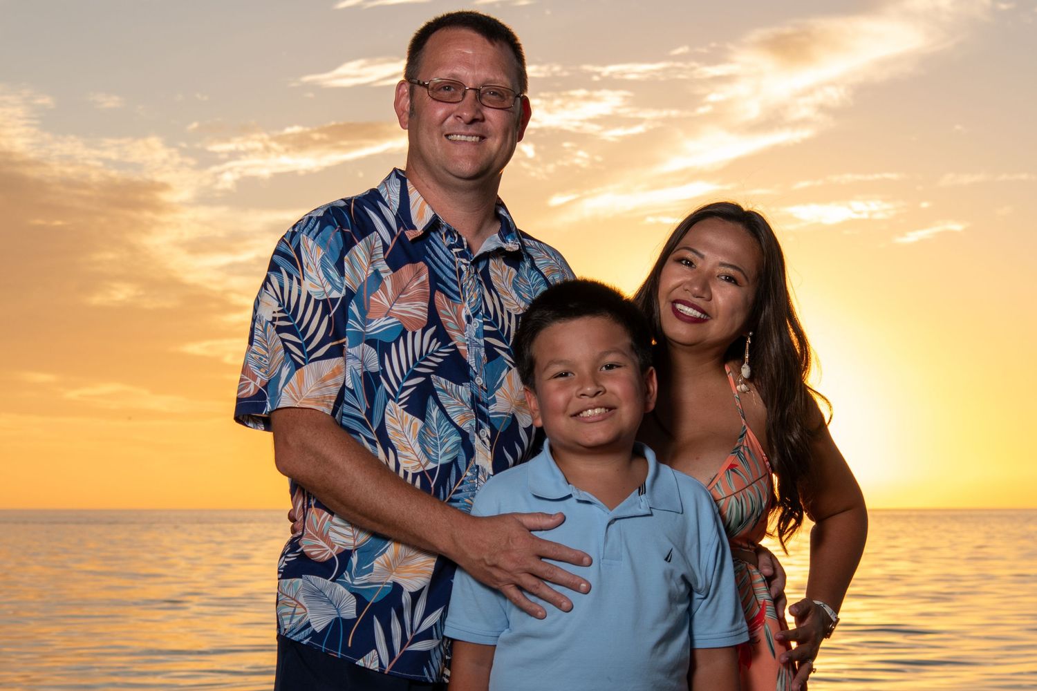 A group in coordinated blue and coral outfits posing on beach at sunset. Beach photoshoot. Family photoshoot,