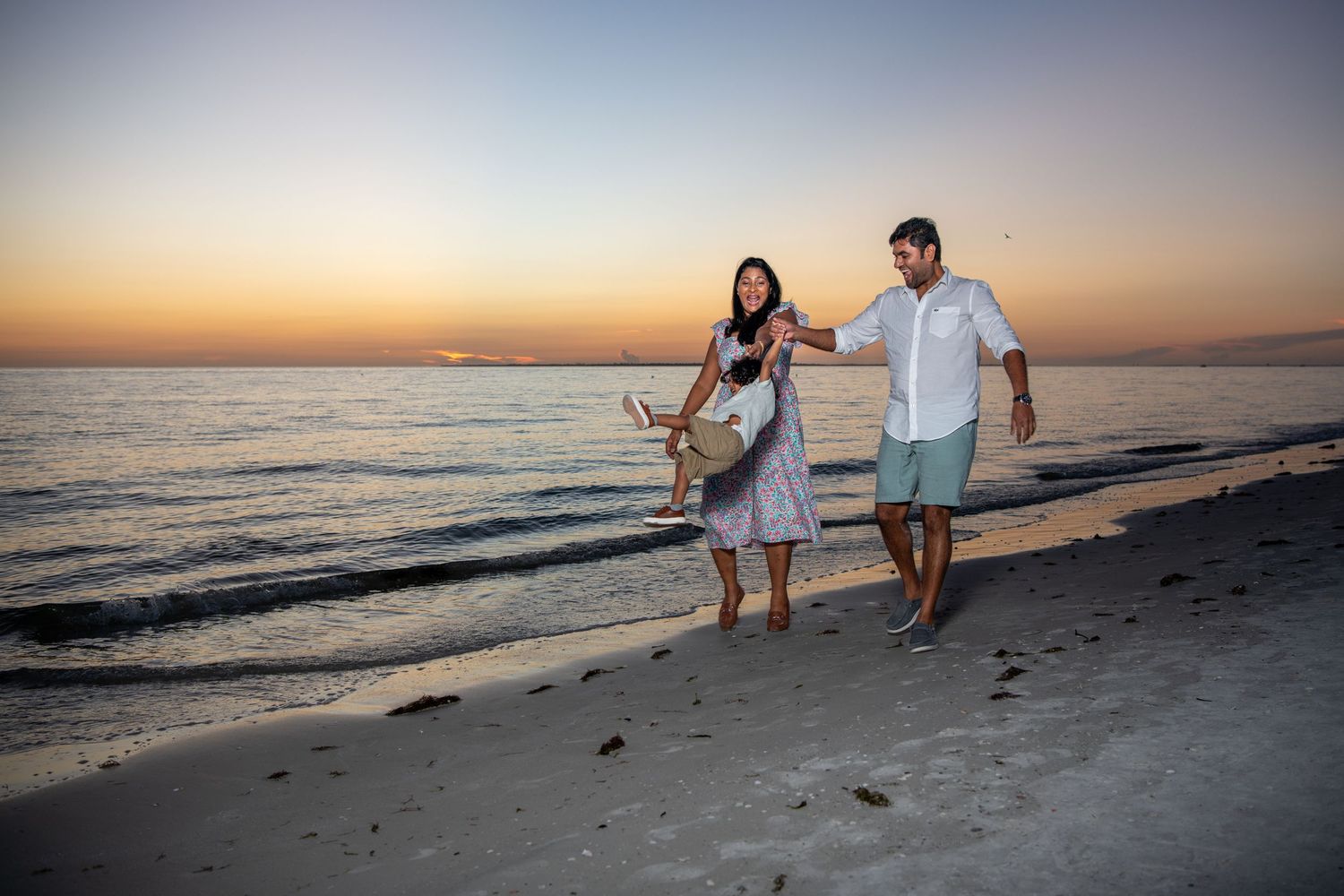 Silhouettes of a family walking along the shoreline during a beautiful beach sunset. Beach photoshoot. Family photoshoot,