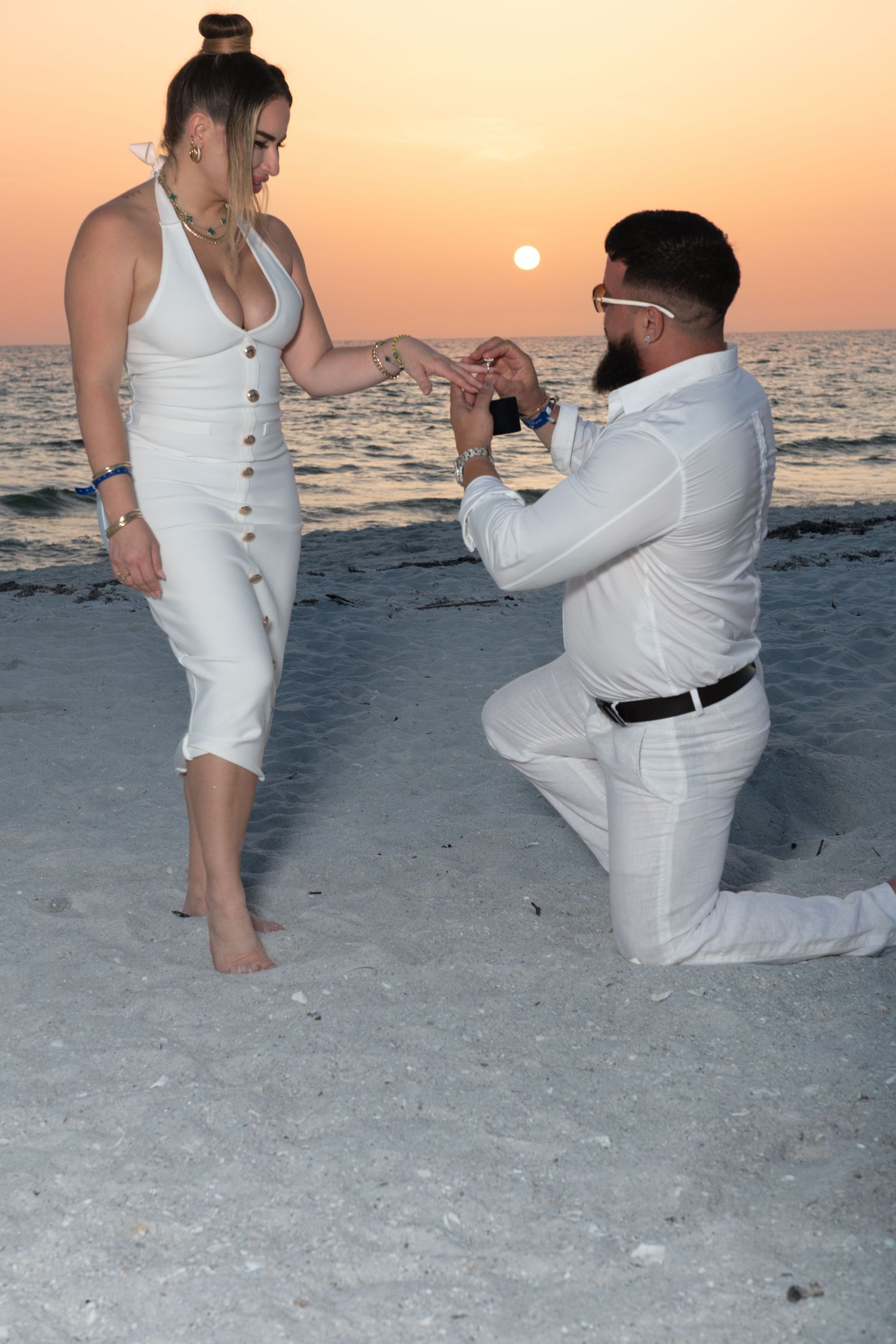 Marriage proposal sequence captured during golden hour on a beach with ocean backdrop.