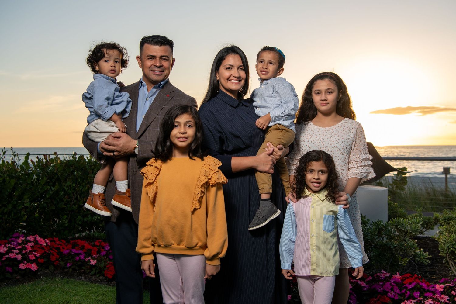 Family portrait series at sunset with children and parents in coordinated casual outfits. Family photoshoot.