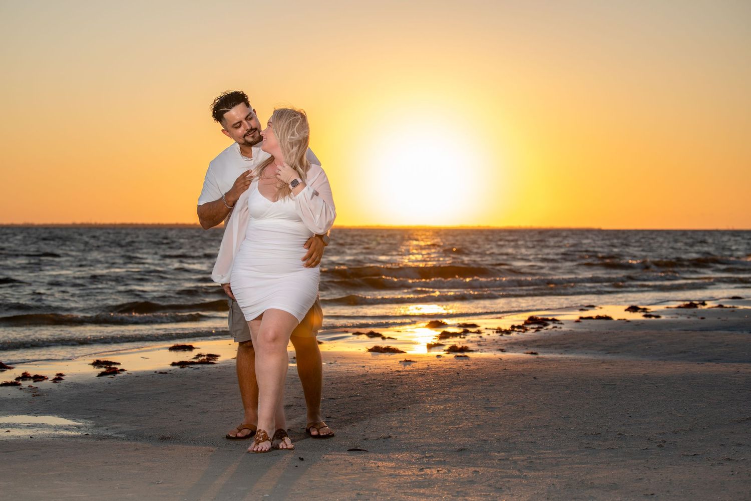 Romantic beach photoshoot during golden sunset with ocean backdrop.