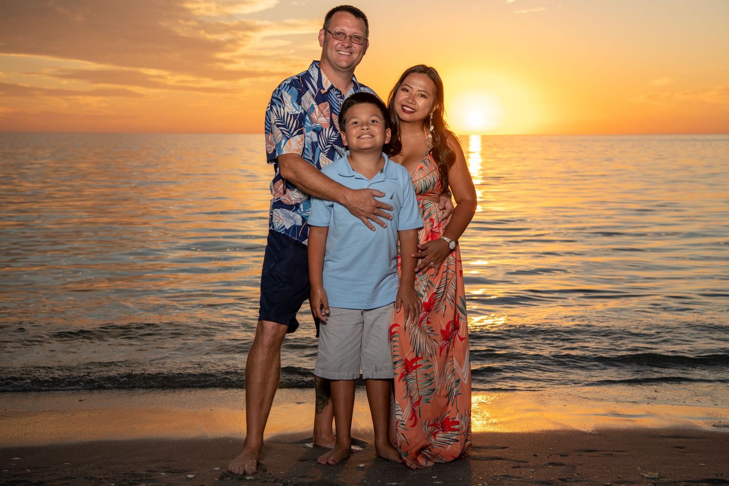 Group in coordinated outfits posing on beach with golden sunset behind them. Beach photoshoot. Family photoshoot,
