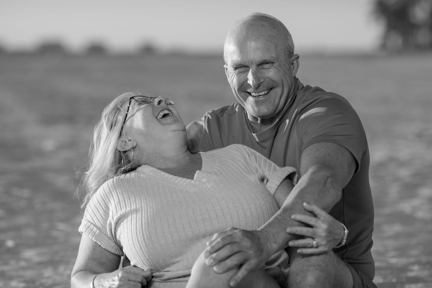 Couple embracing on a beach at sunset with ocean waves in the background. Couples photoshoot.