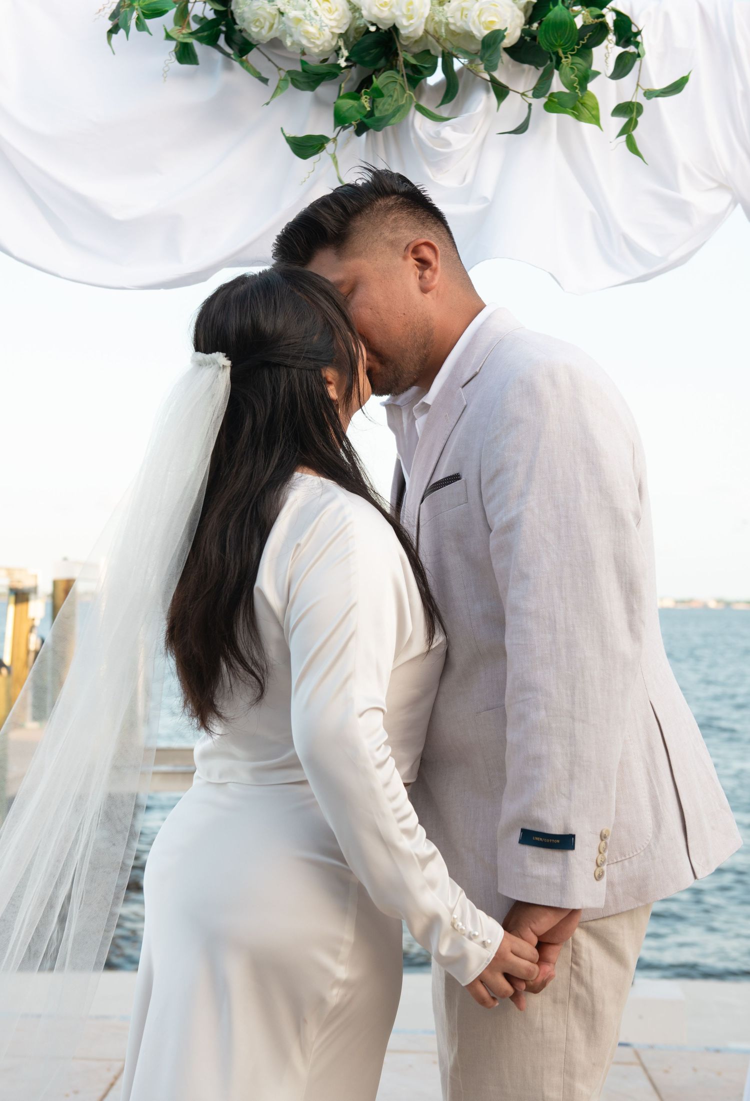 Romantic wedding ceremony by the ocean with white floral decorations.