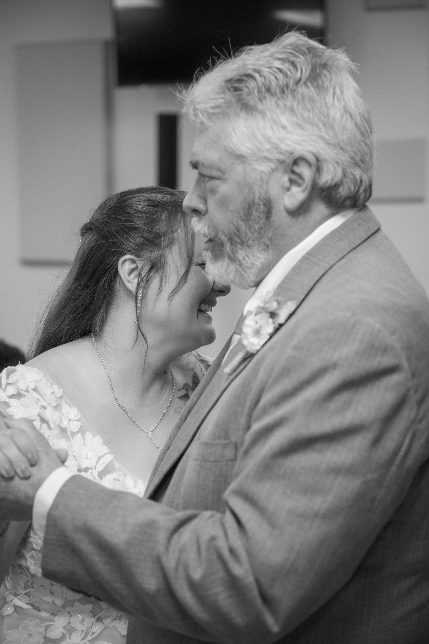 Black and white photo capturing an emotional embrace during a wedding celebration.