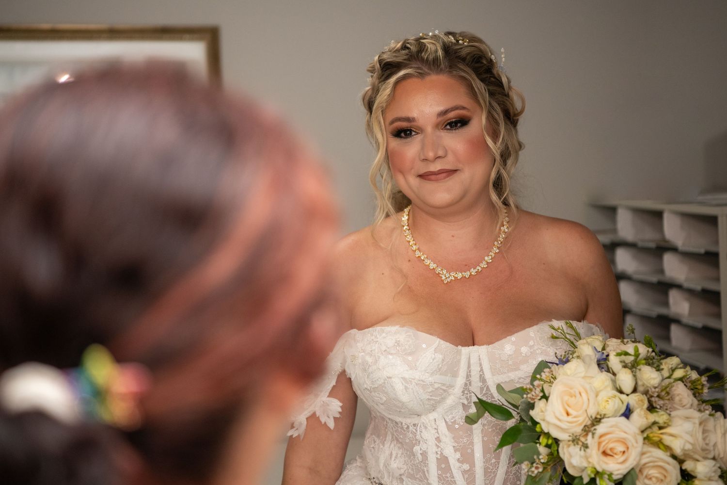 Bride holding cream rose bouquet in traditional lace wedding gown.