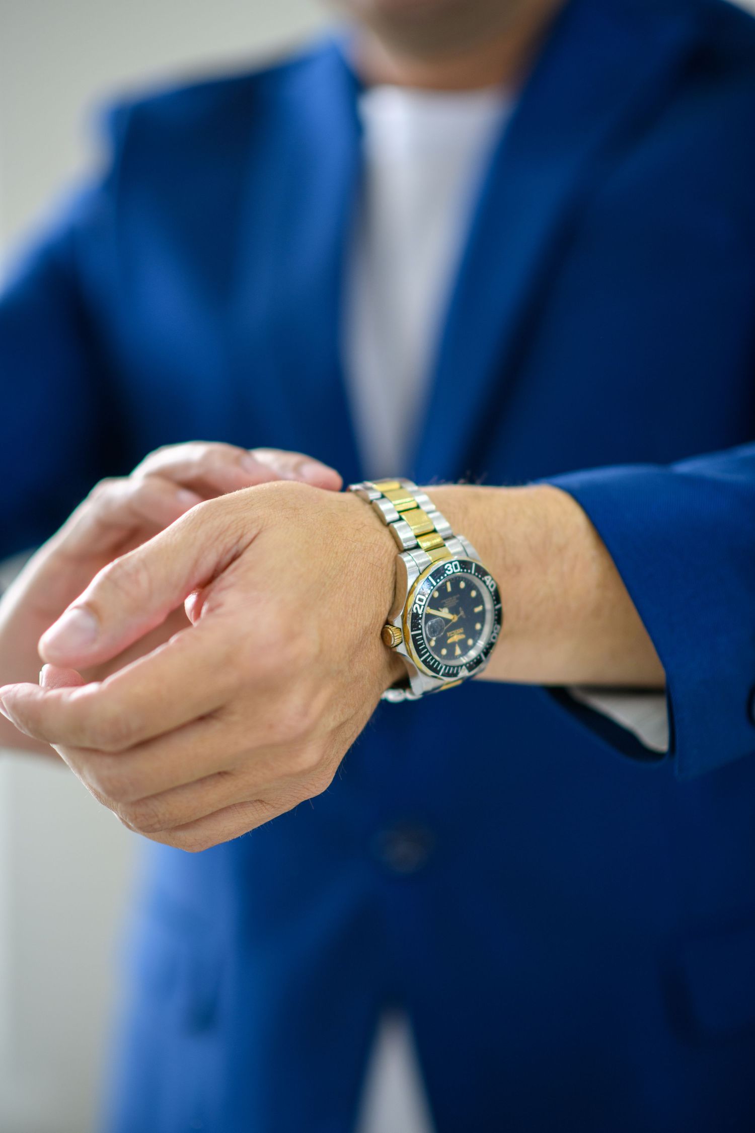 Close-up shots of gold watch and hands in blue suit sleeve.