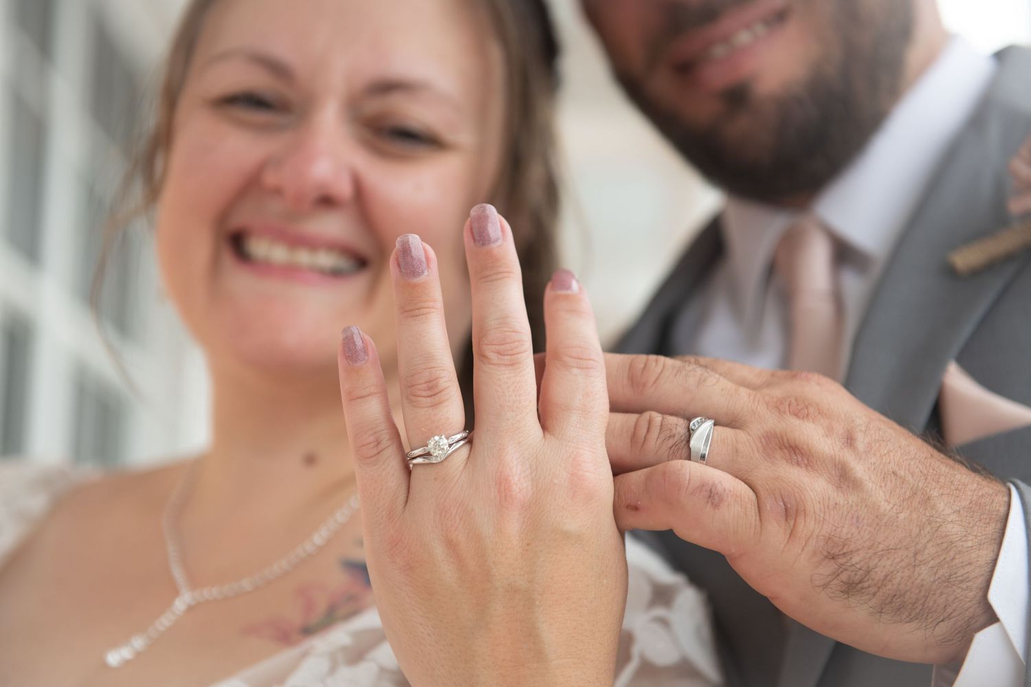 Close-up shot of hands showing off wedding rings and jewelry in natural lighting.