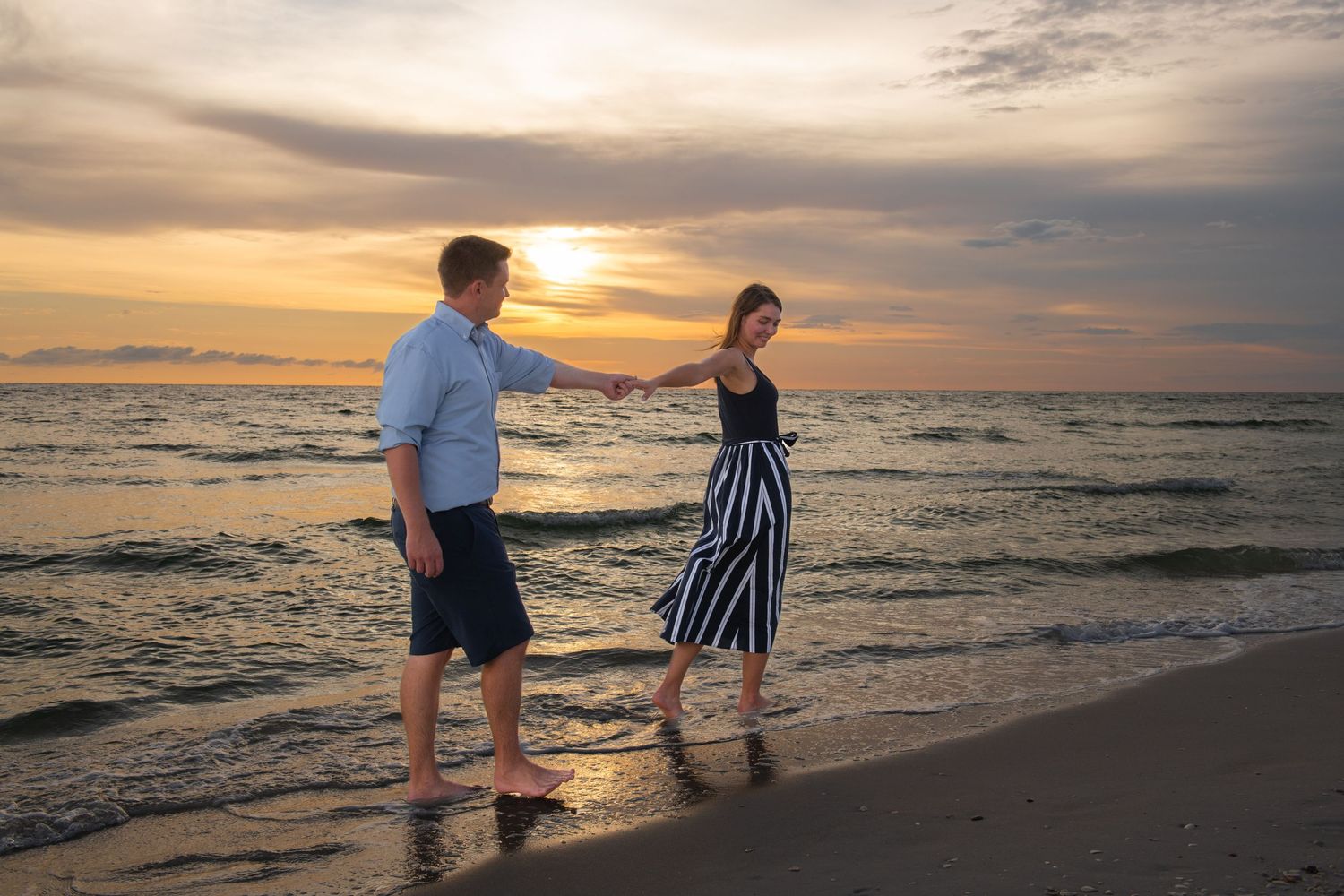 Silhouettes of people walking on a beach at sunset with golden light reflecting off the ocean waves.