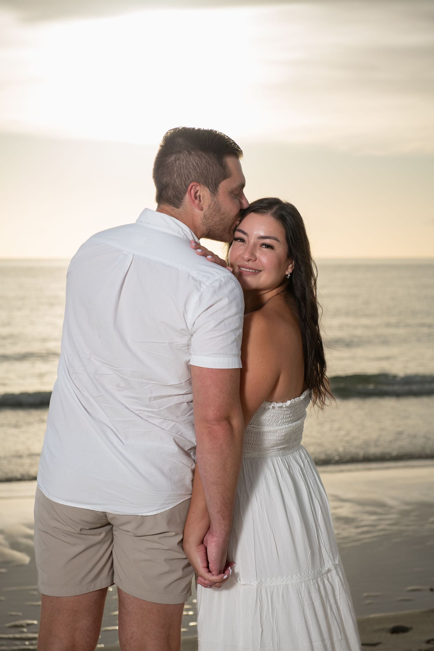 Intimate sunset beach portraits with gentle ocean waves in background.