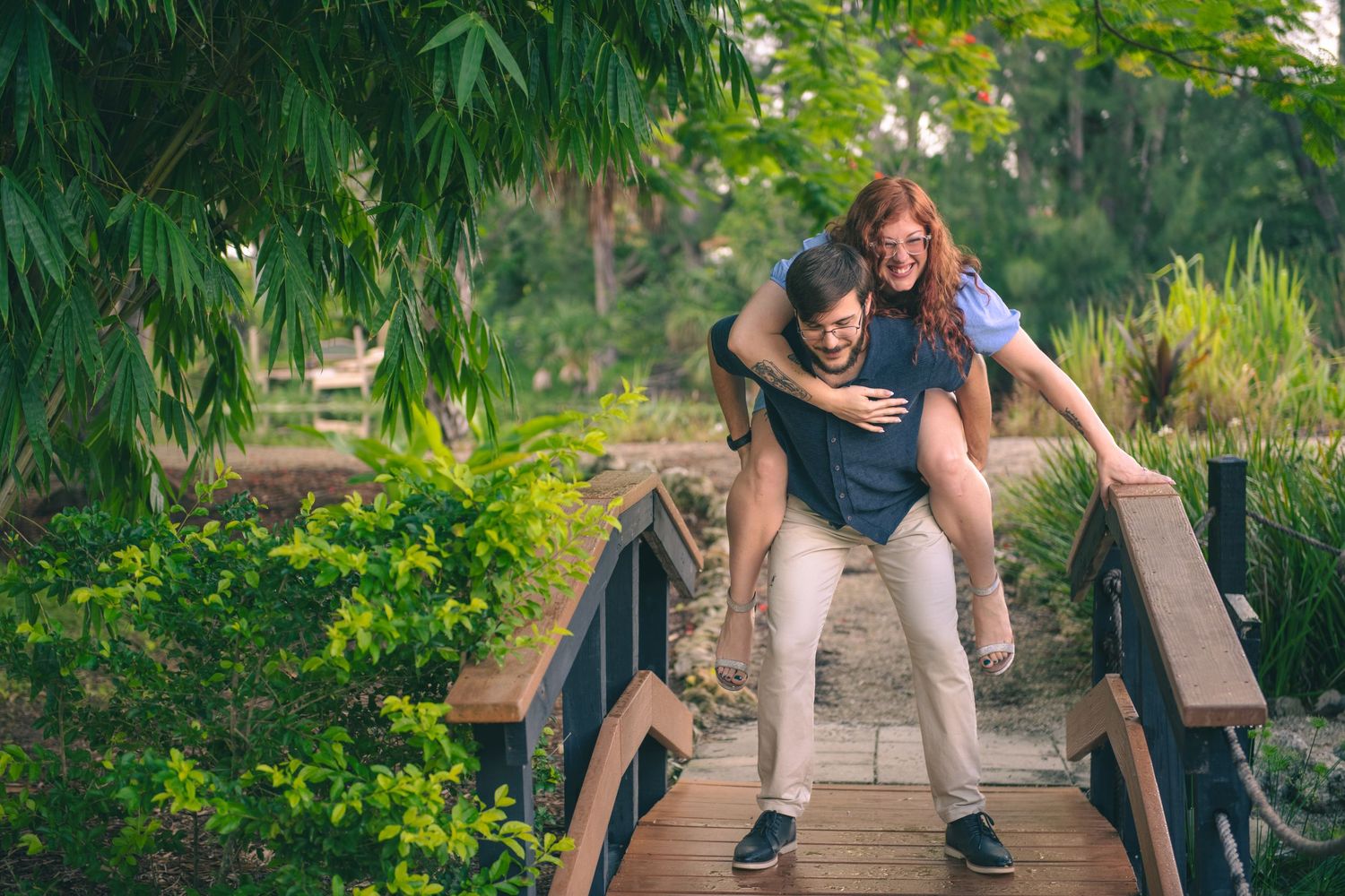 Romantic photoshoot on a wooden walkway surrounded by tropical plants and greenery.