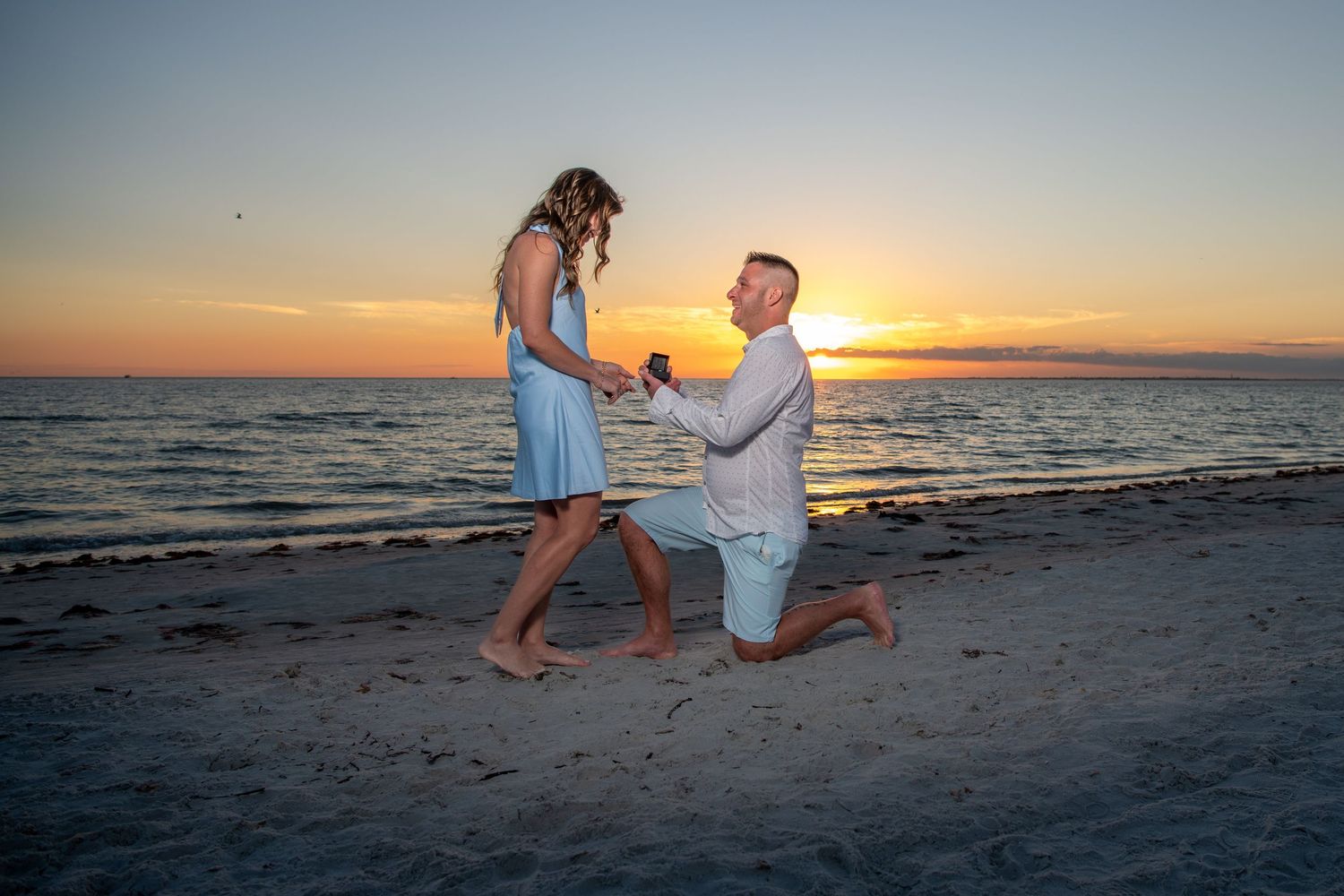 Sunset beach proposal captured in silhouette against orange sky. Engagement photoshoot. Couples photos.