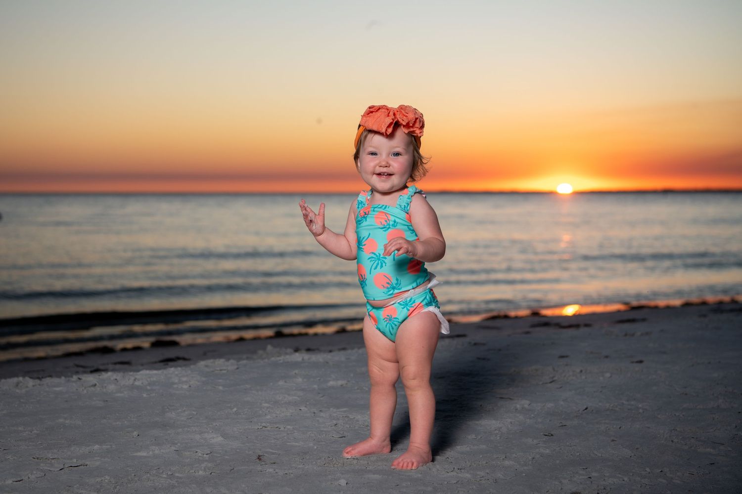 Beautiful beach sunset with turquoise swimwear against orange sky.