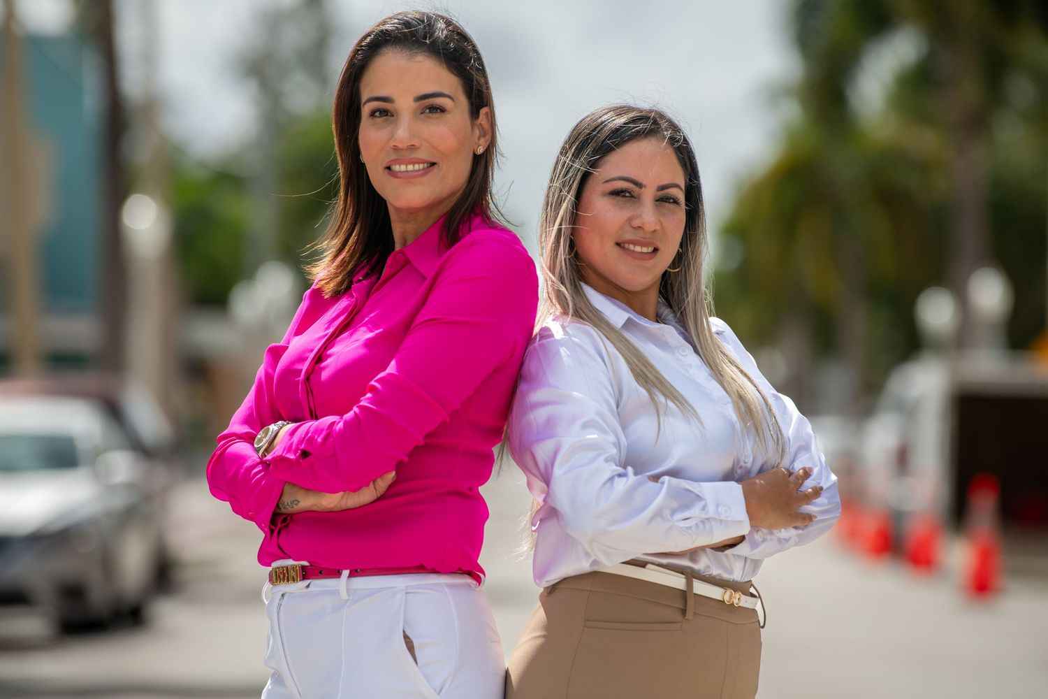 Two professionals in bright pink and white outfits walking together outdoors.