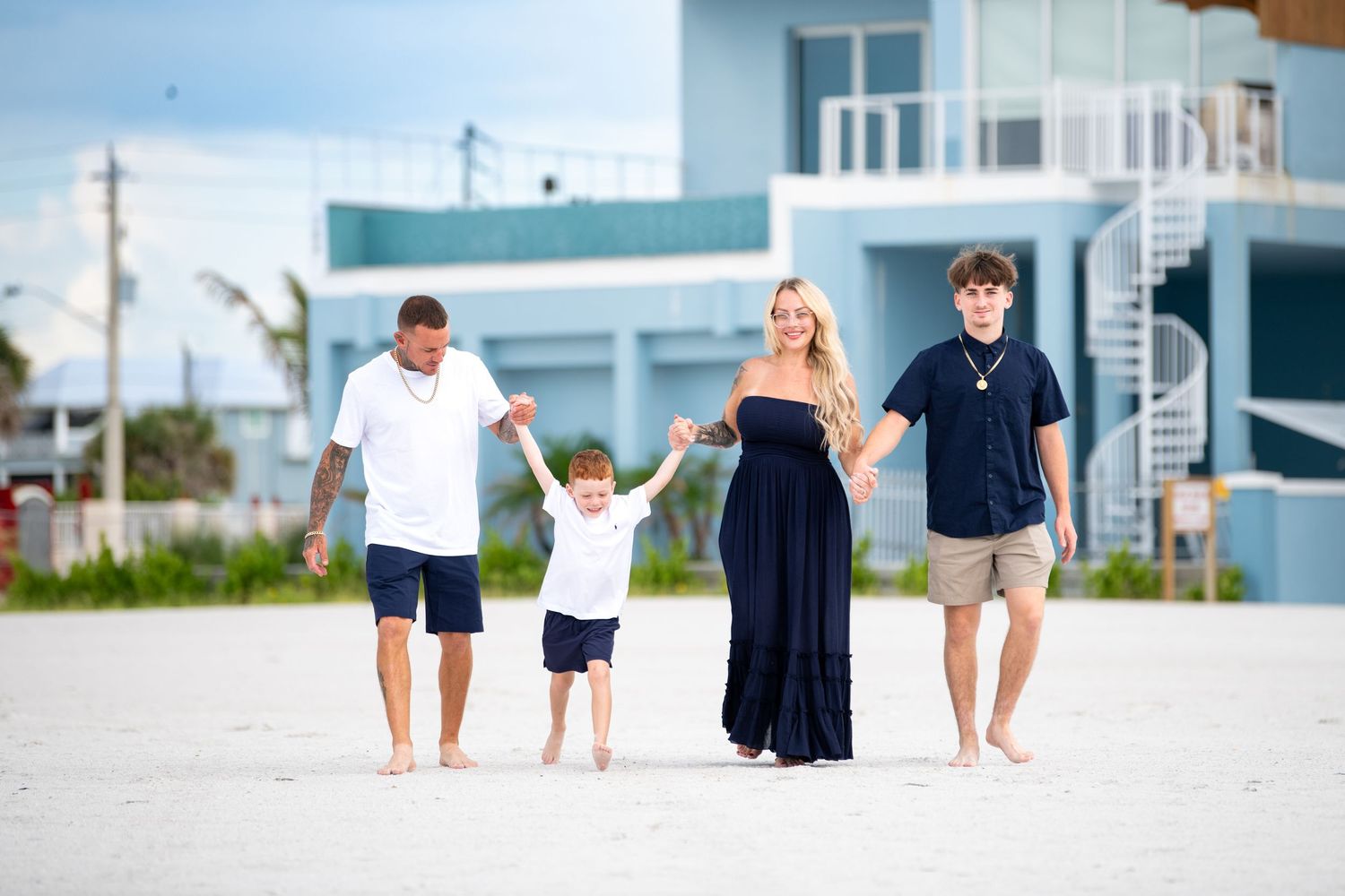 Group walking together on white sandy beach with buildings in background.