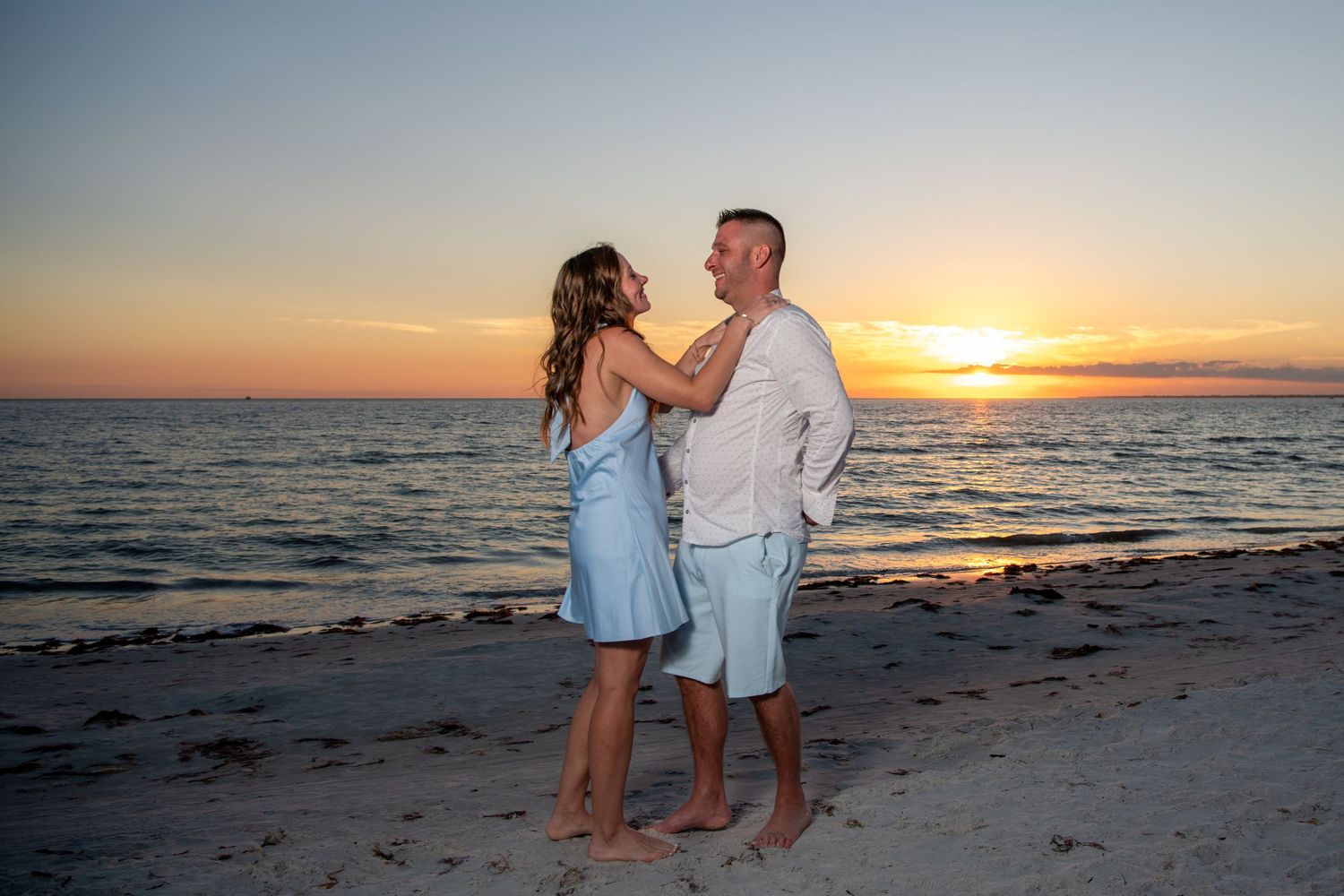 Romantic beach photoshoot during golden hour with waves crashing behind. Engagement photoshoot. Couples photos.
