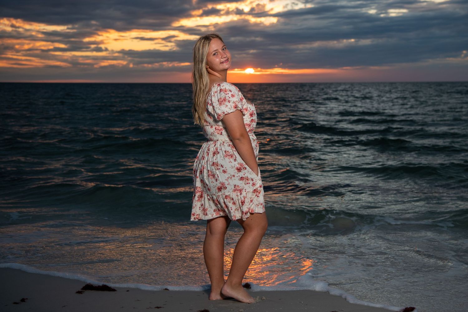Silhouette of someone in a floral dress dancing on the beach at sunset. Self portraits. Senior photos.