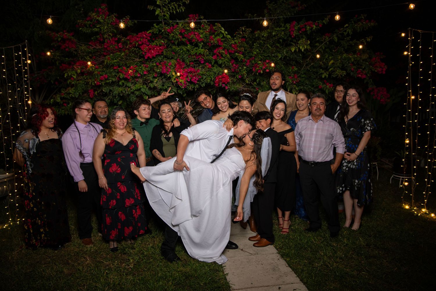 Wedding reception guests dancing and celebrating under string lights. Wedding photography.