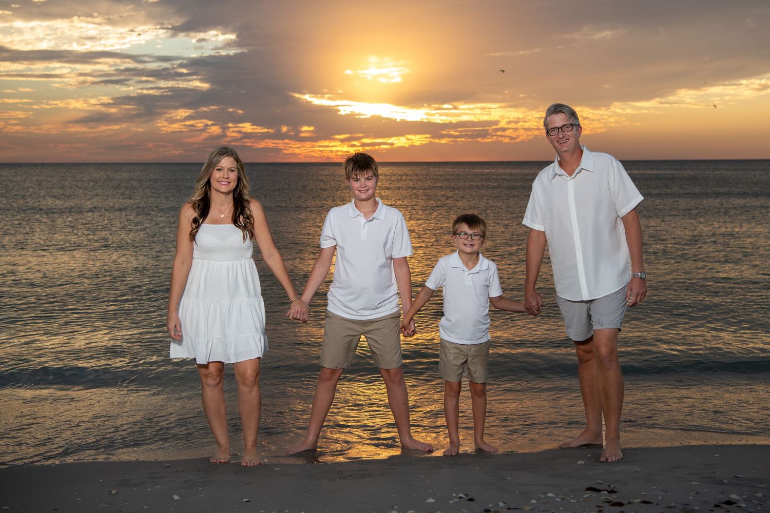 Family beach portraits with multiple poses against vibrant sunset ocean backdrop. Beach photoshoot. Family photoshoot,