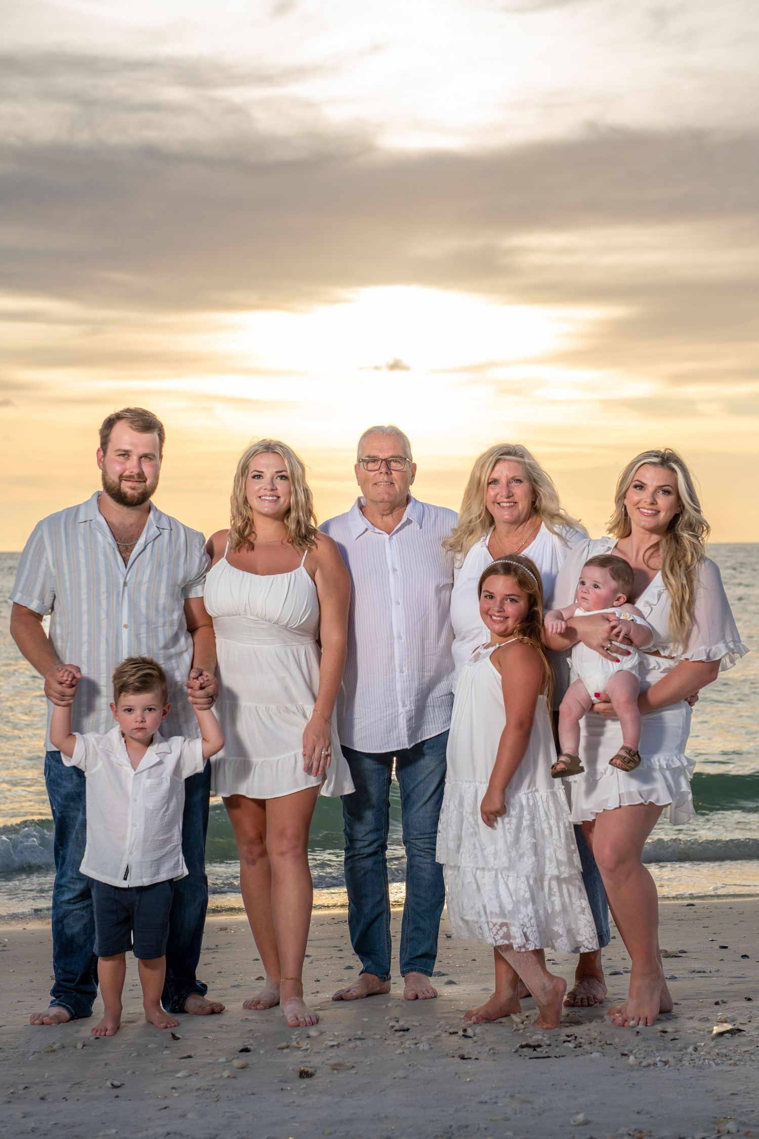 Multi-generational family group photo session on beach at golden hour.