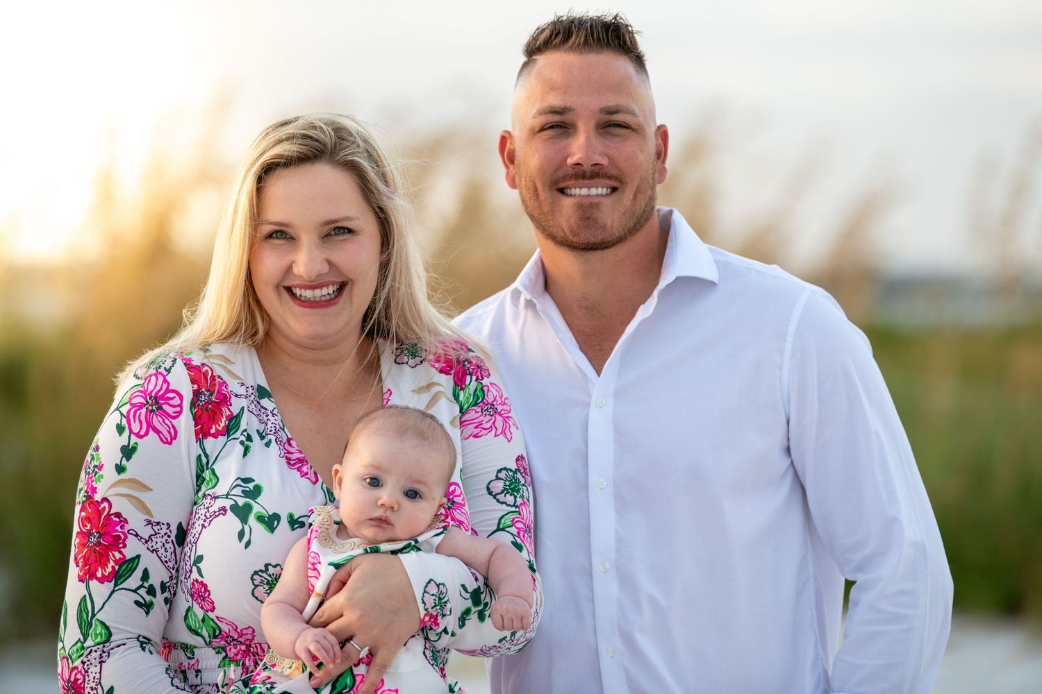A family portrait session on the beach with everyone wearing coordinated white and floral outfits.