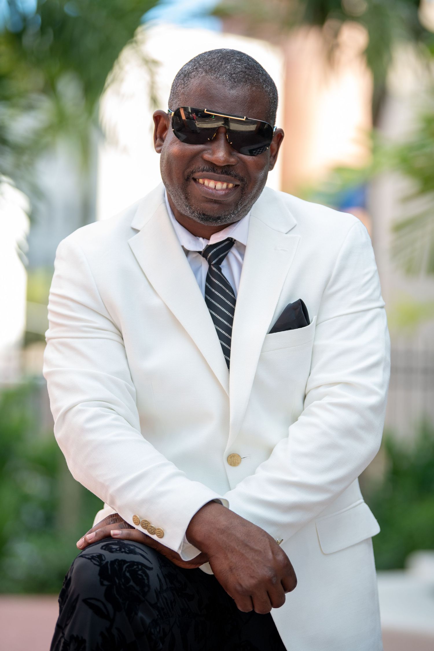 Stylish portrait of a person in white suit jacket and striped tie outdoors.