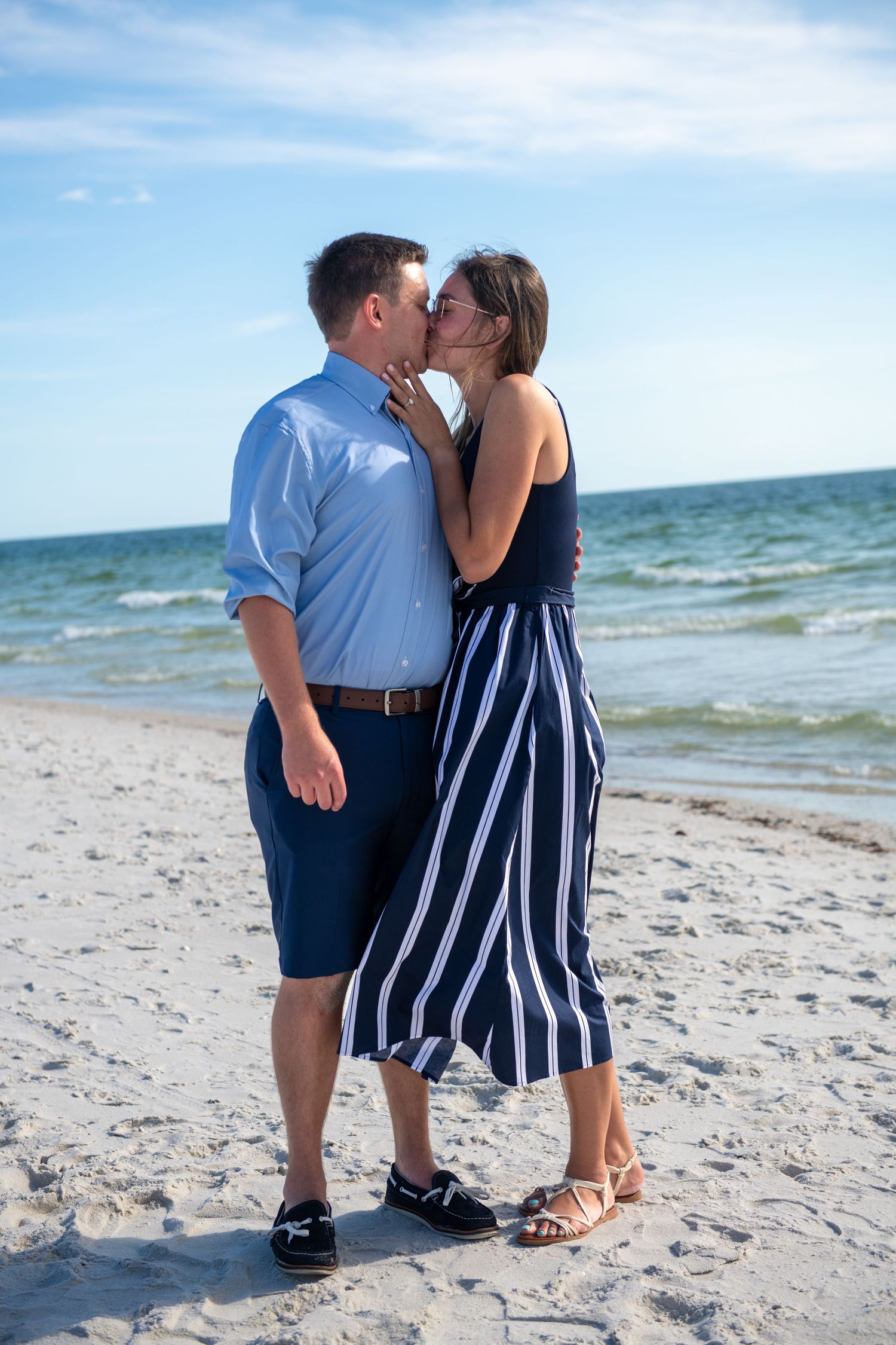 Romantic beach scene with couple in coordinated blue and white outfits.