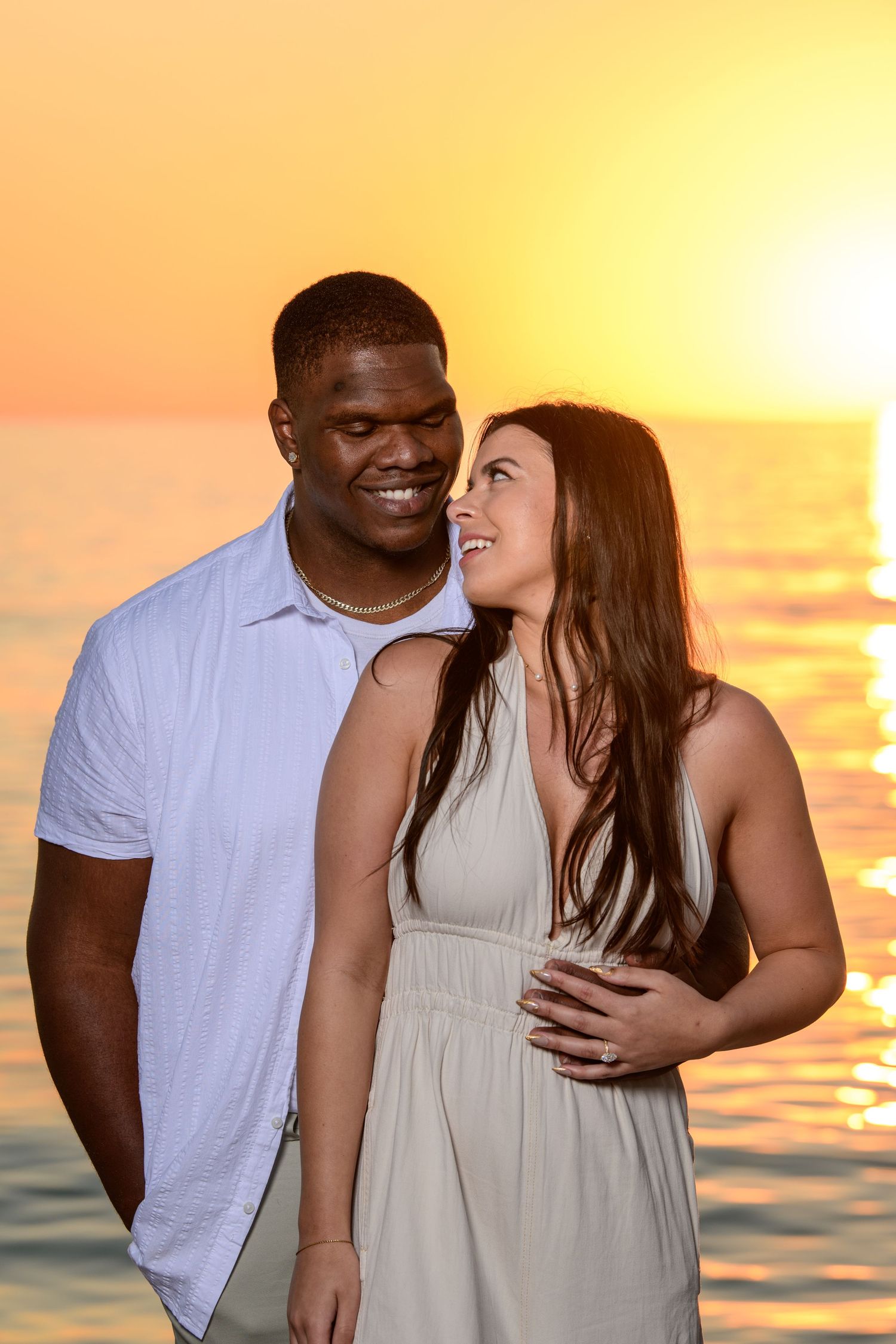 Happy couple sharing joyful moments on beach during golden hour sunset. Engagement photoshoot. Couples photos.