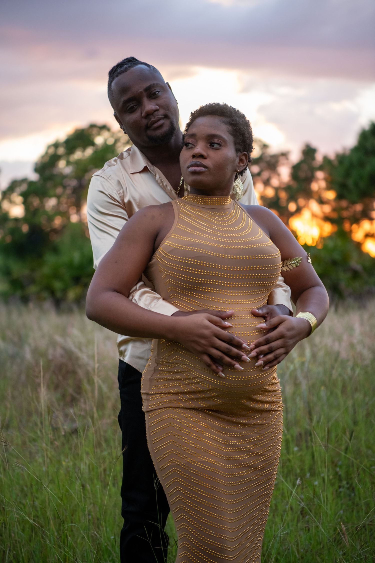 Romantic sunset maternity photo in field with couple in elegant attire. Maternity photoshoot.