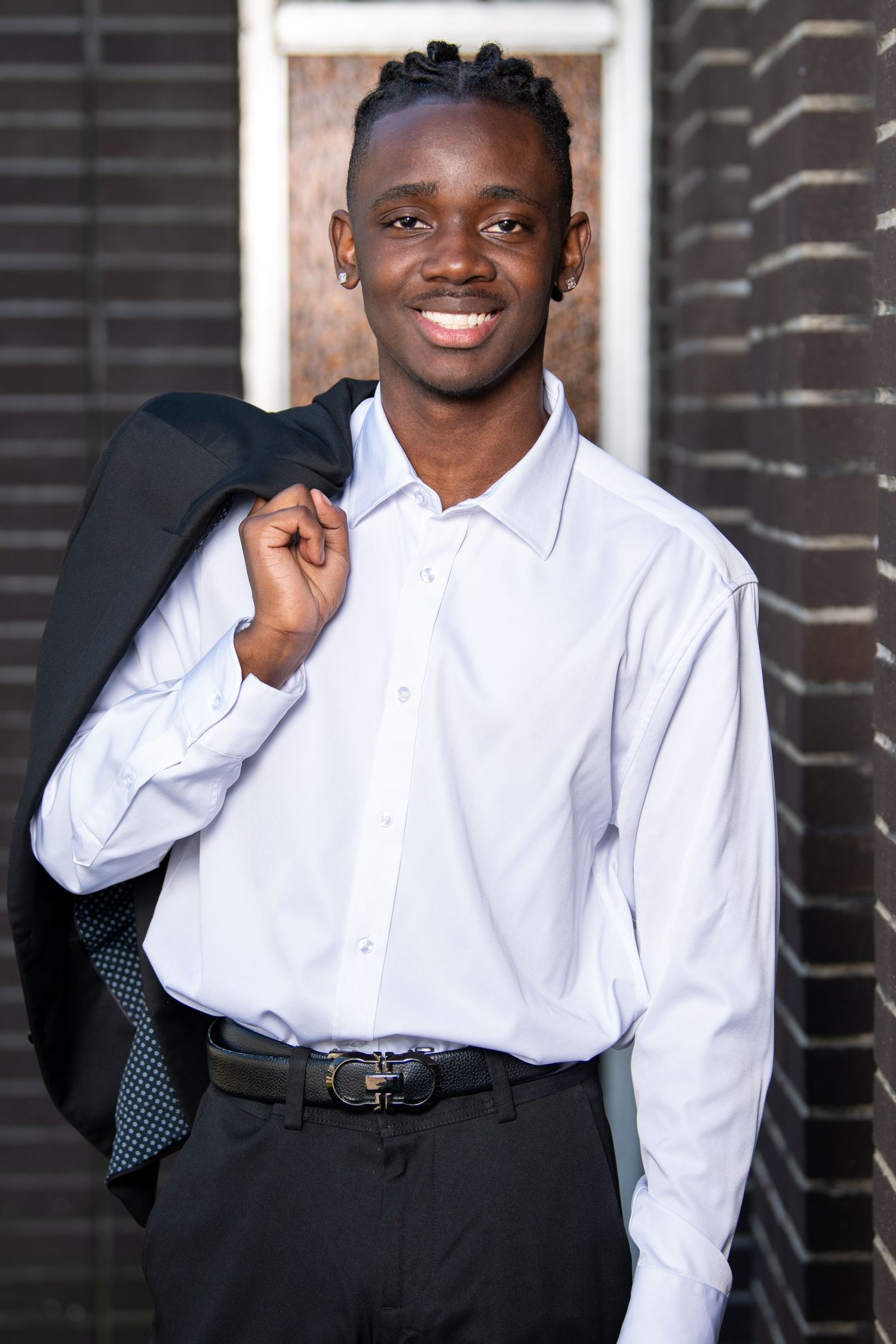 Professional portrait series of a person in a white dress shirt and black suit against a brick wall. Professional headshots. Self portraits.