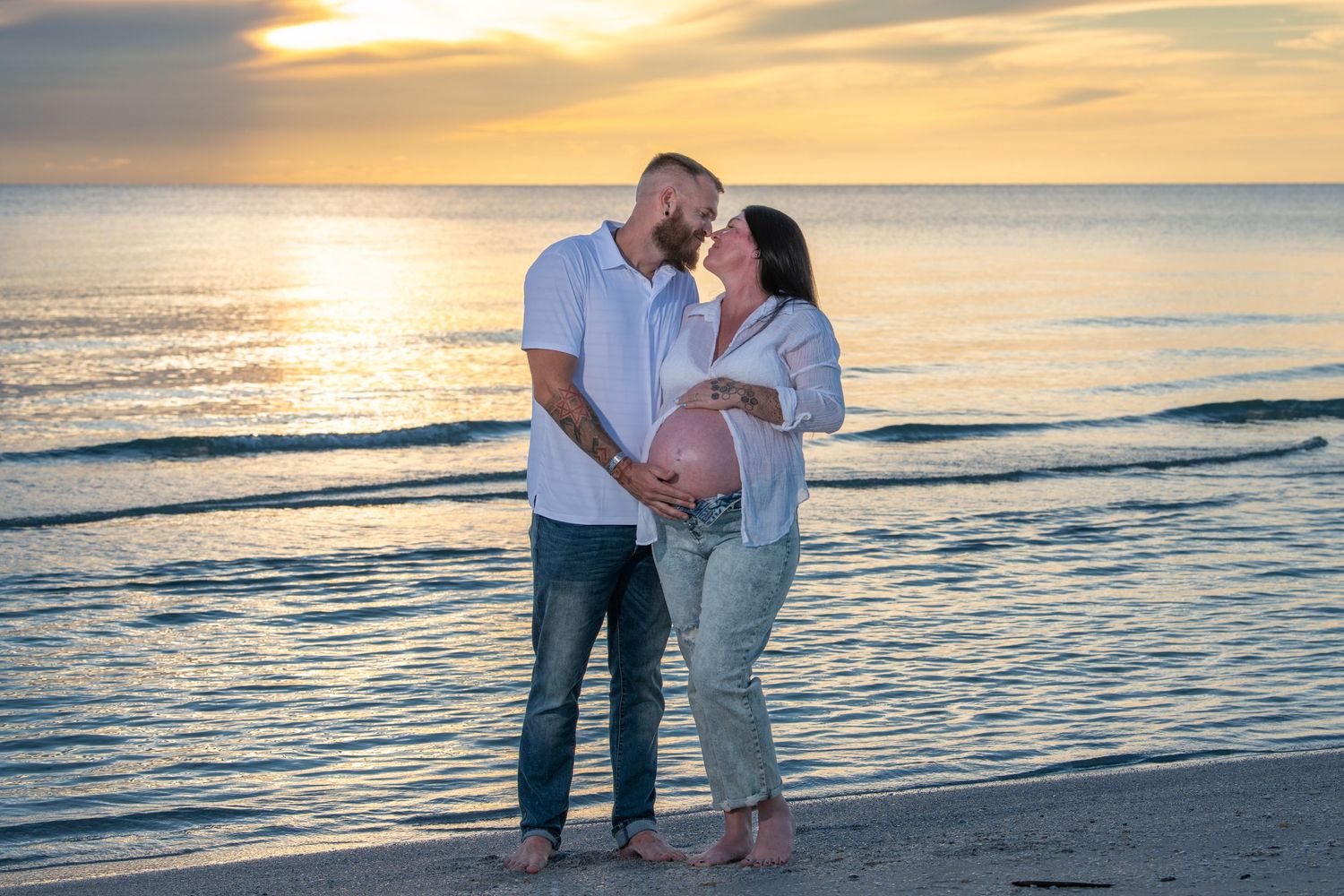 Romantic beach photoshoot with couple walking along shoreline at sunset. Maternity photoshoot.