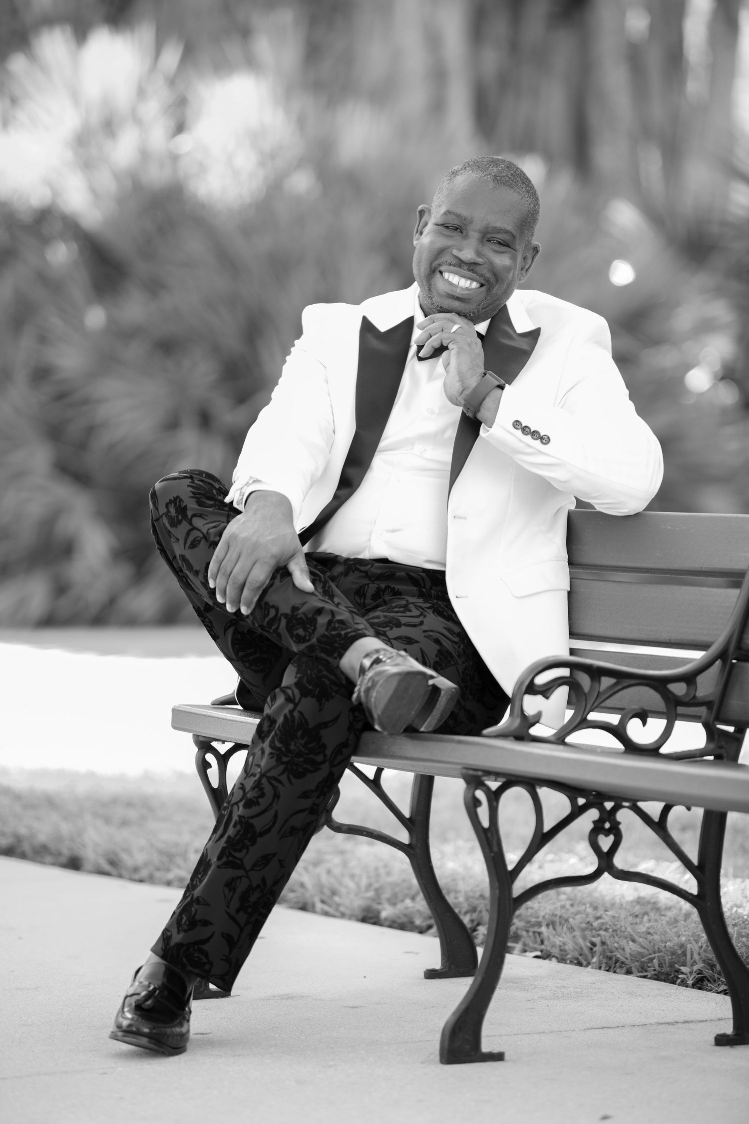 Black and white photo of a person relaxing on a park bench in formal attire.