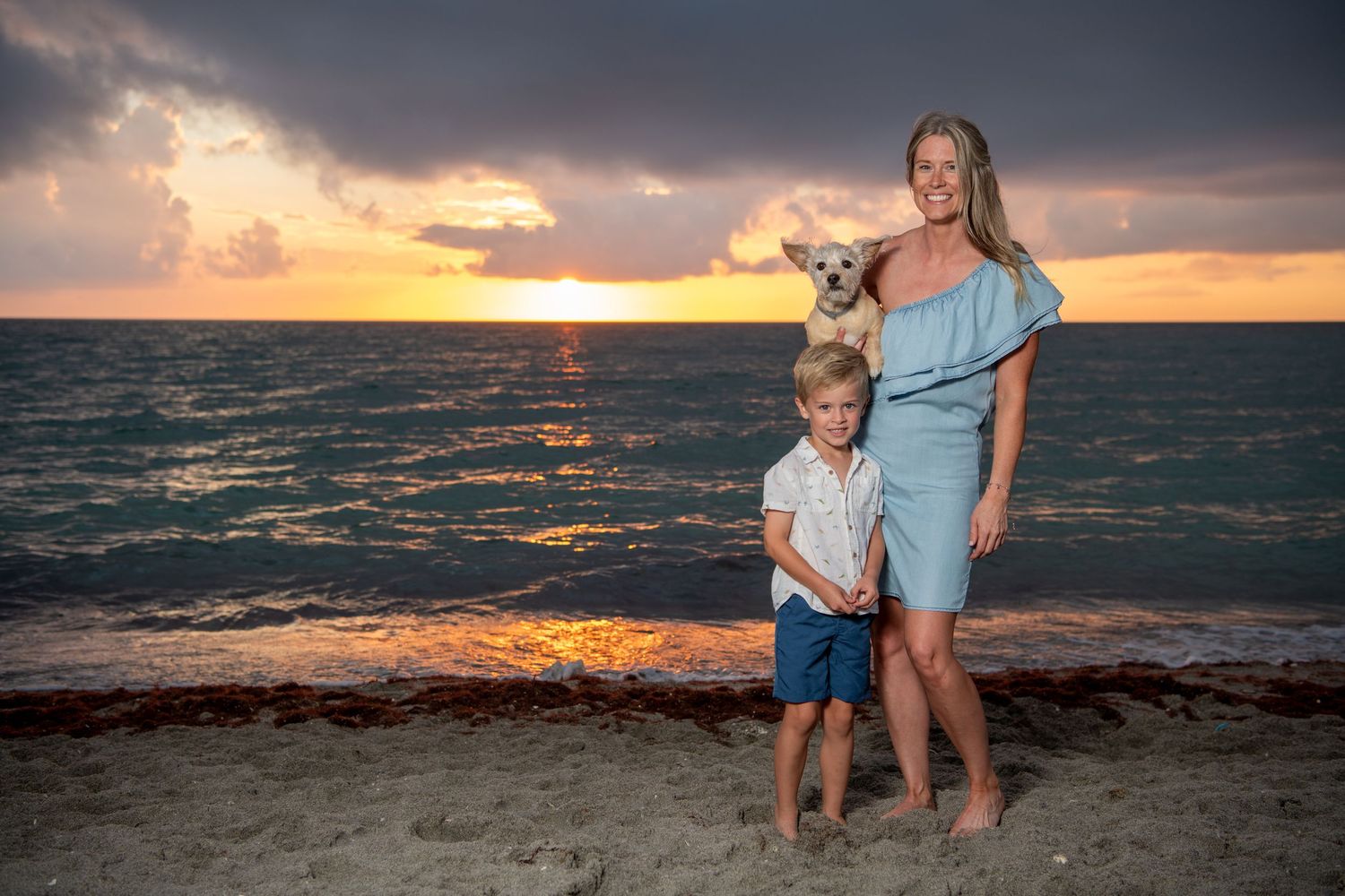 Family enjoying a peaceful evening on the beach as the sun sets over the horizon. Beach photoshoot.