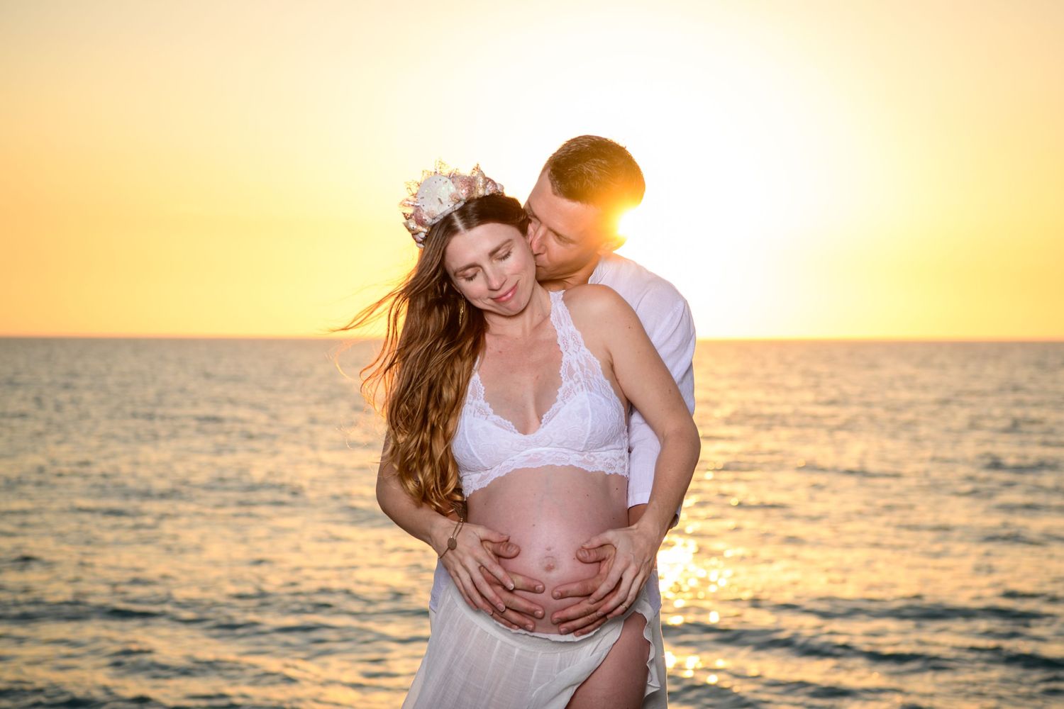 Intimate sunset beach photoshoot with golden light and ocean backdrop. Maternity photoshoot,