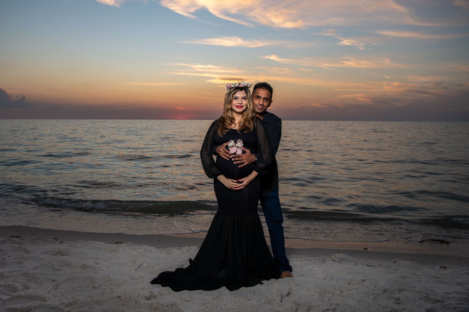 A maternity portrait of a couple in formal attire posing on the beach during golden hour. Maternity photoshoot. Couples photos.