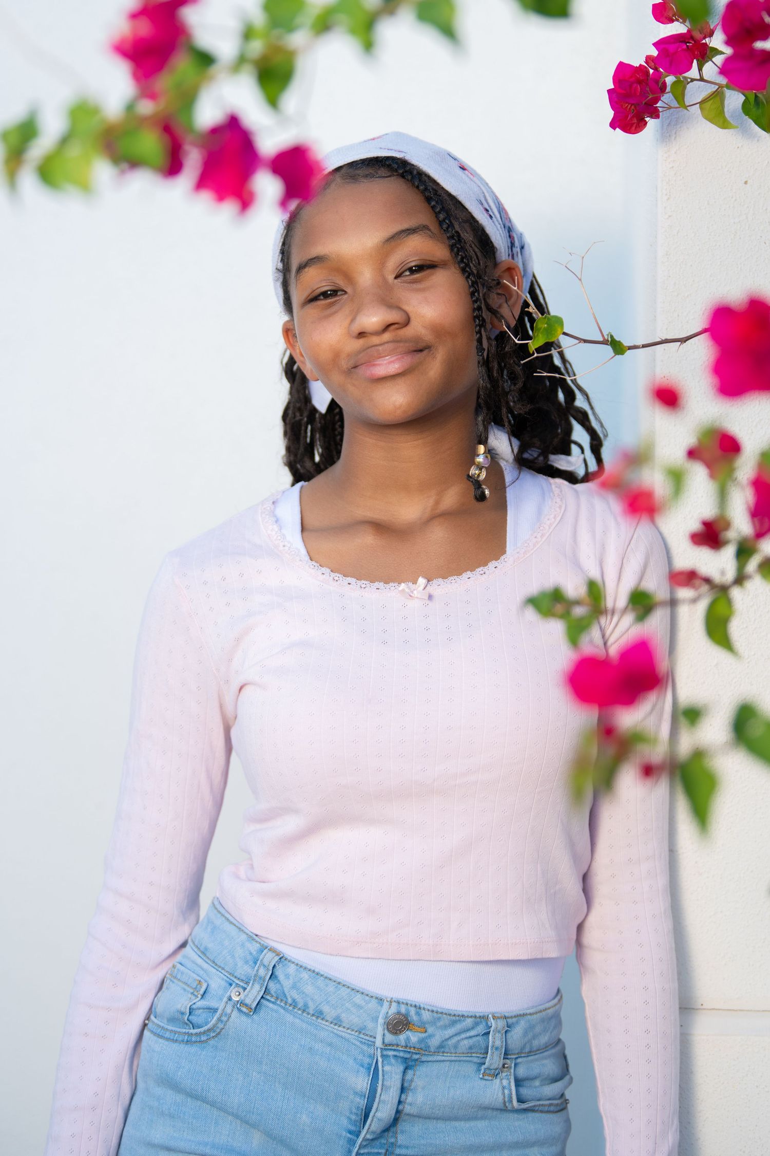 Casual portrait with bright pink flowers and white wall background.Headshots.