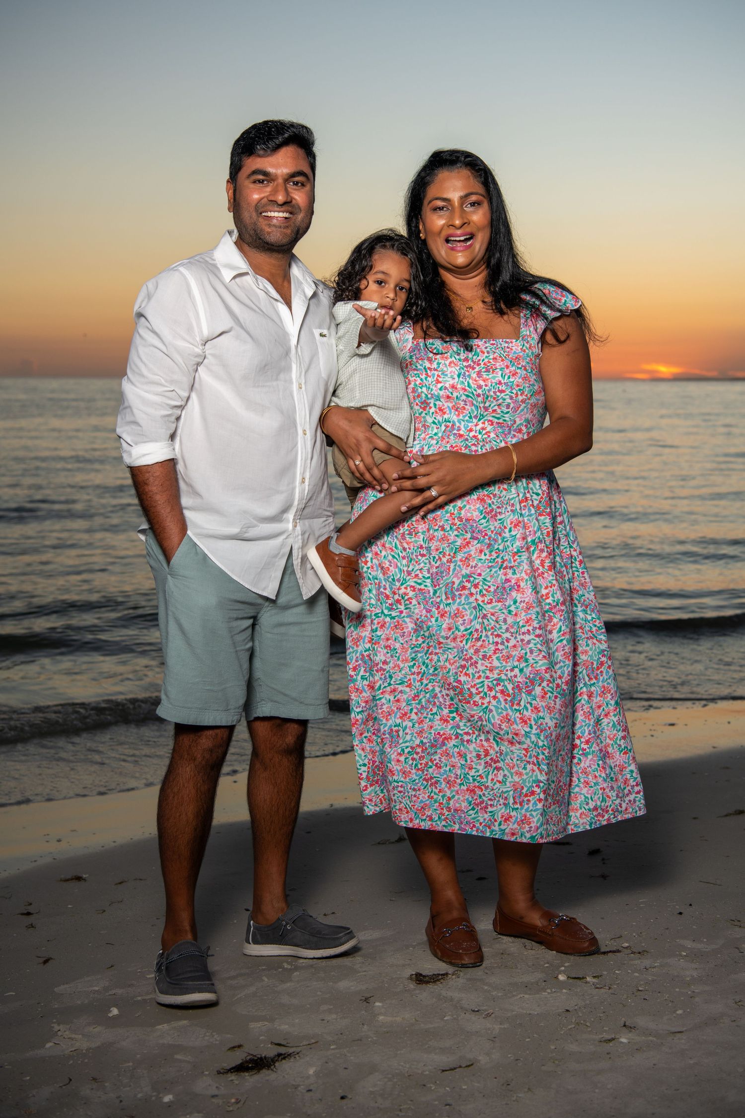 A family takes casual portraits on the beach at sunset wearing coordinated outfits. Beach photoshoot. Family photoshoot,