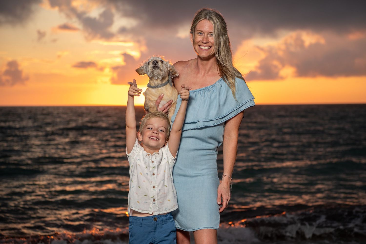 A sunset beach portrait session featuring a mother and child against dramatic sky colors. Beach photoshoot. Family photoshoot,