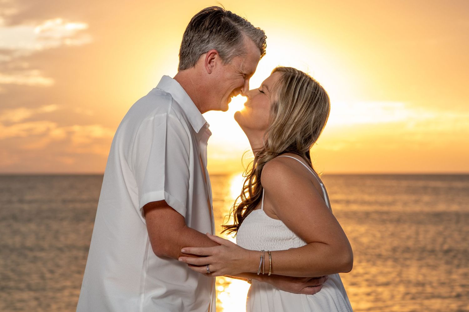 Intimate couple embracing on beach with glowing sunset and ocean backdrop. Beach photoshoot. Family photoshoot,