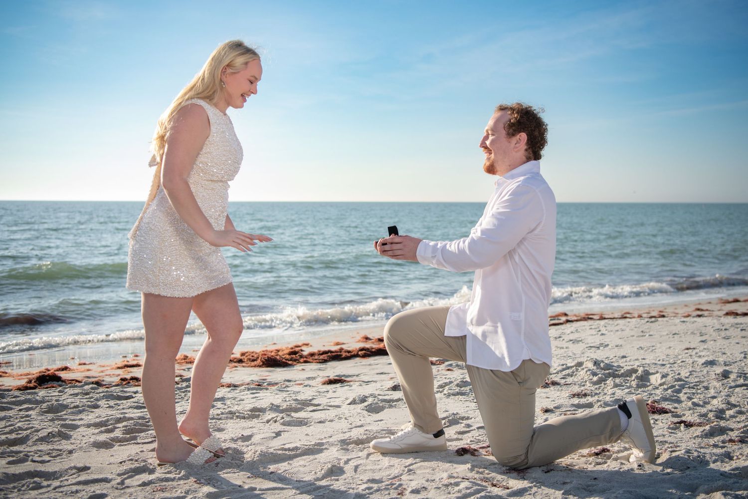 A beachside marriage proposal scene with a ring box and surprised reaction. Engagement photoshoot. Couples photos.