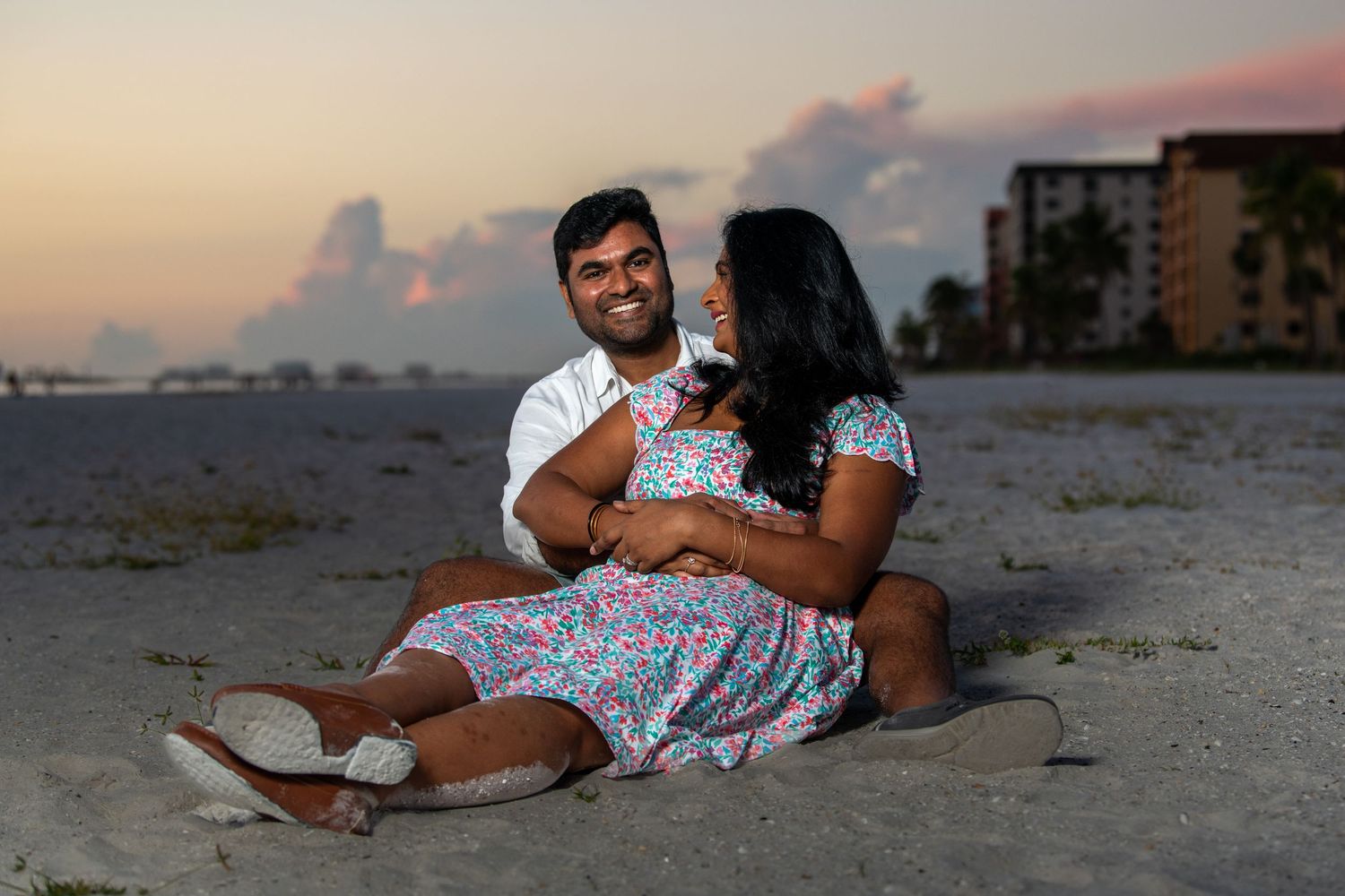 A family relaxes together on the sand during a beach photoshoot at dusk. Beach photoshoot. Family photoshoot,
