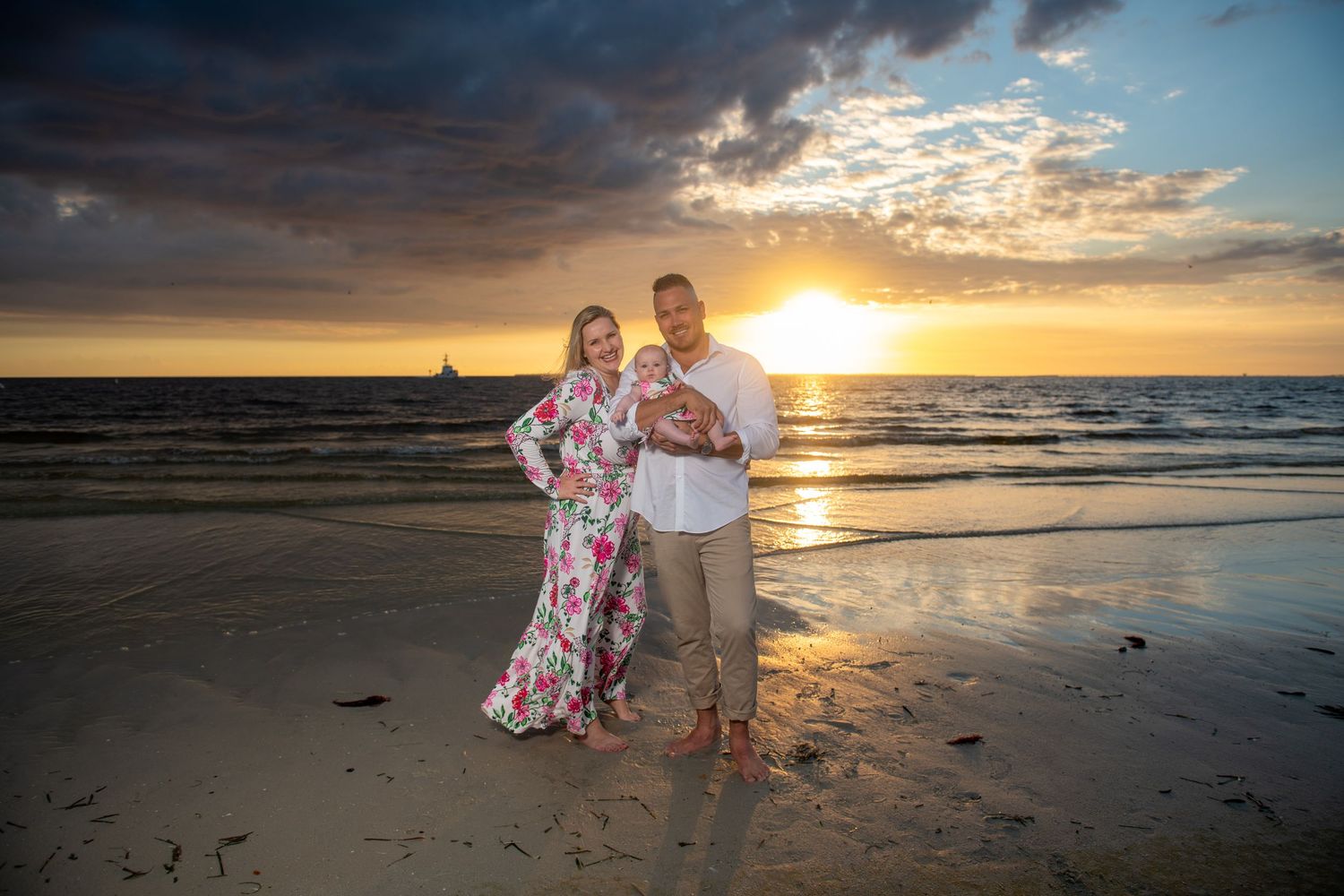 A beach photoshoot at sunset with dramatic clouds and golden light reflecting on the sand.